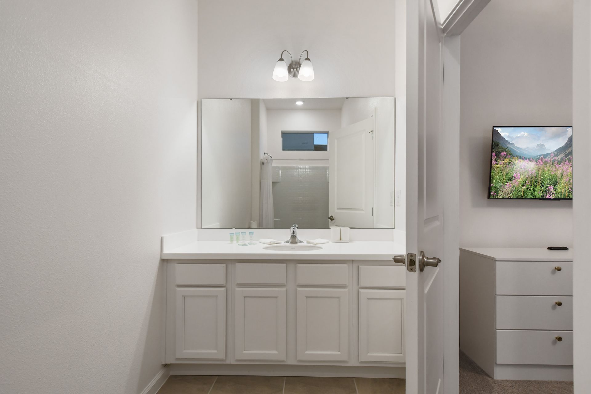 Spacious ensuite bathroom with extended vanity, large mirror, and bright modern finish

