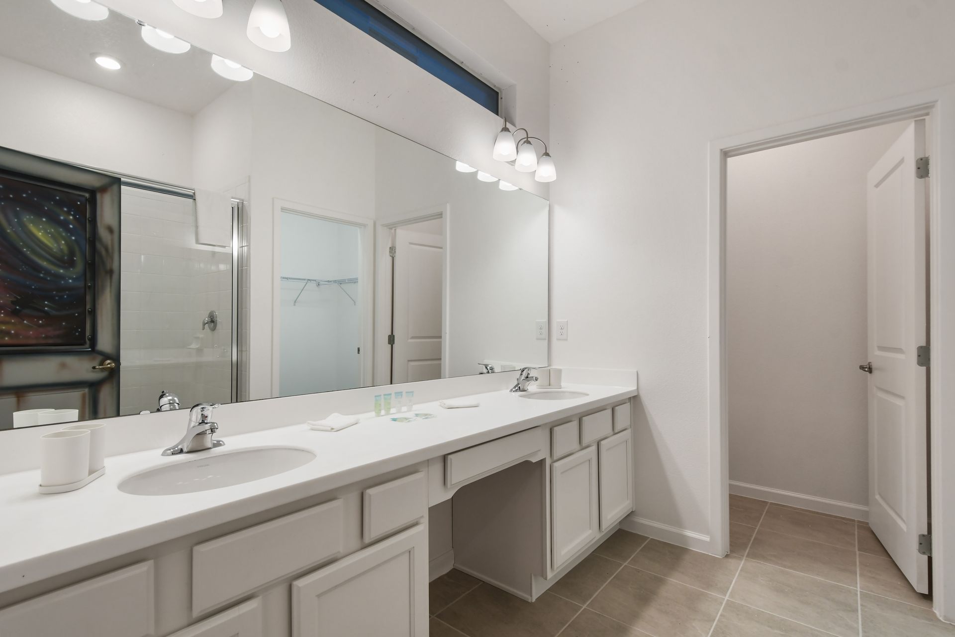 Elegant master bathroom with dual sinks, vanity seating, and walk-in closet access
