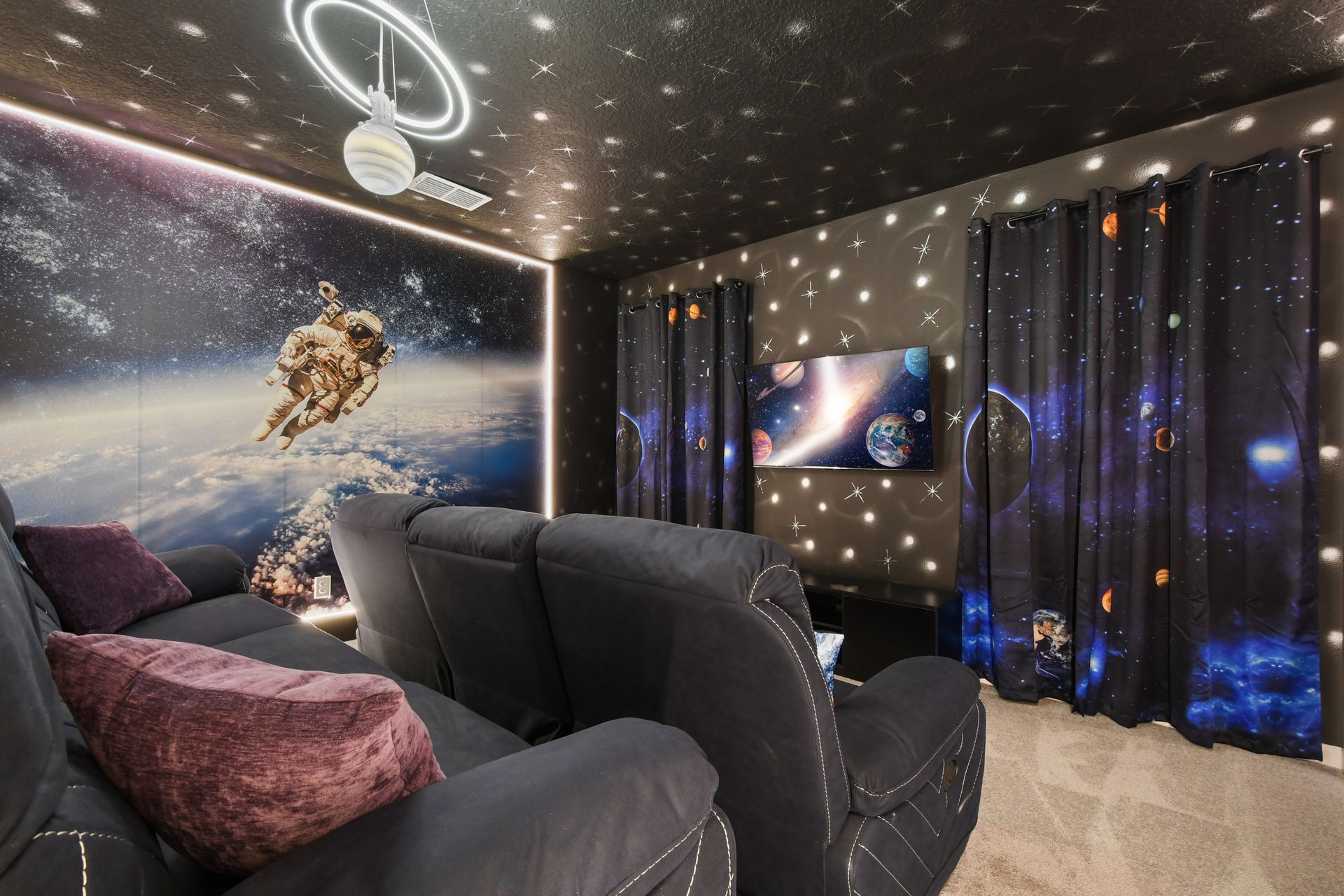 Space-themed home theater with reclining seats, galaxy décor, and immersive visuals
