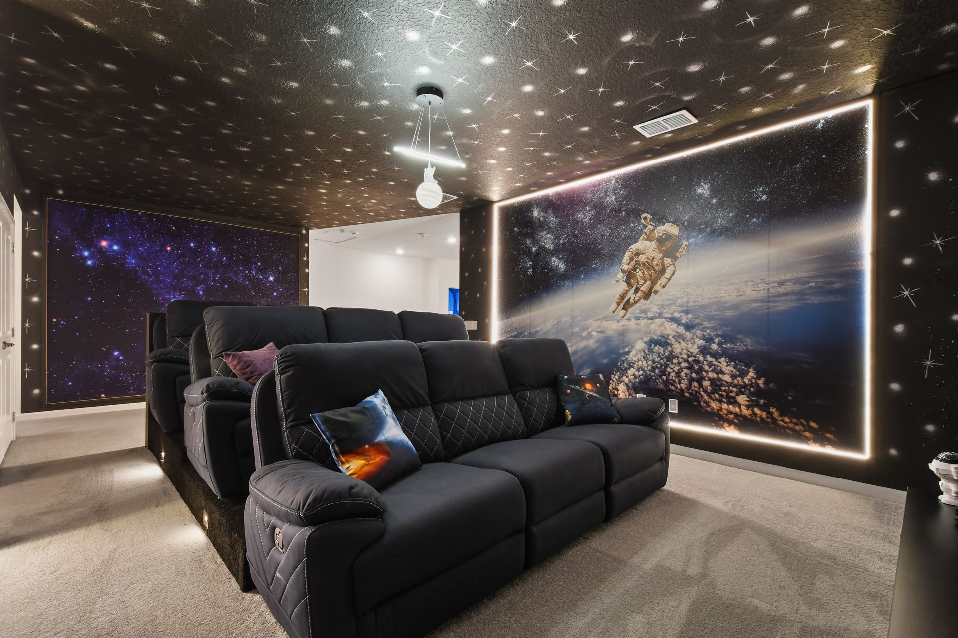 Space-themed home theater with reclining seats, galaxy décor, and immersive visuals
