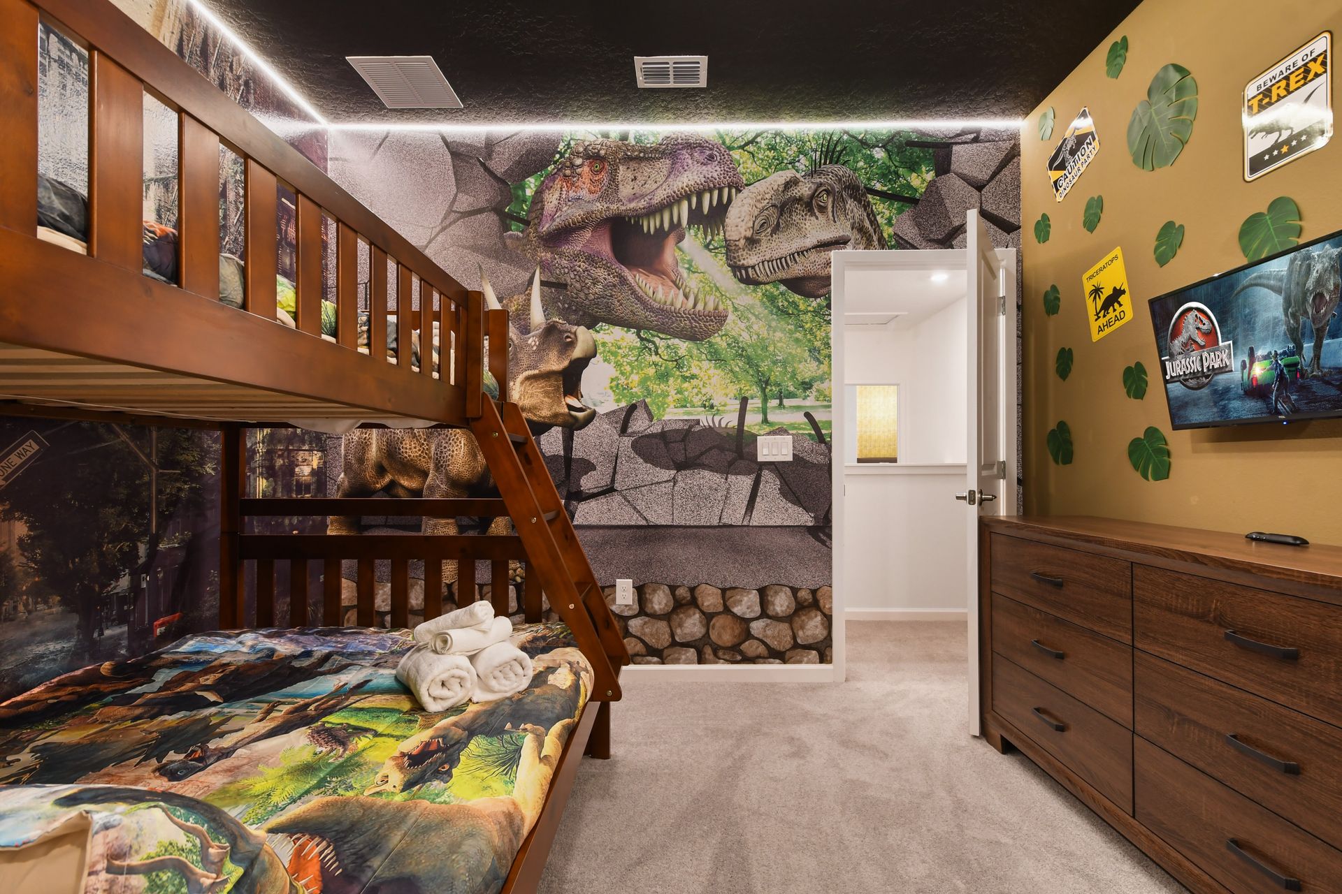 Dino adventure bunk room with jungle décor, city ruins, and themed bedding
