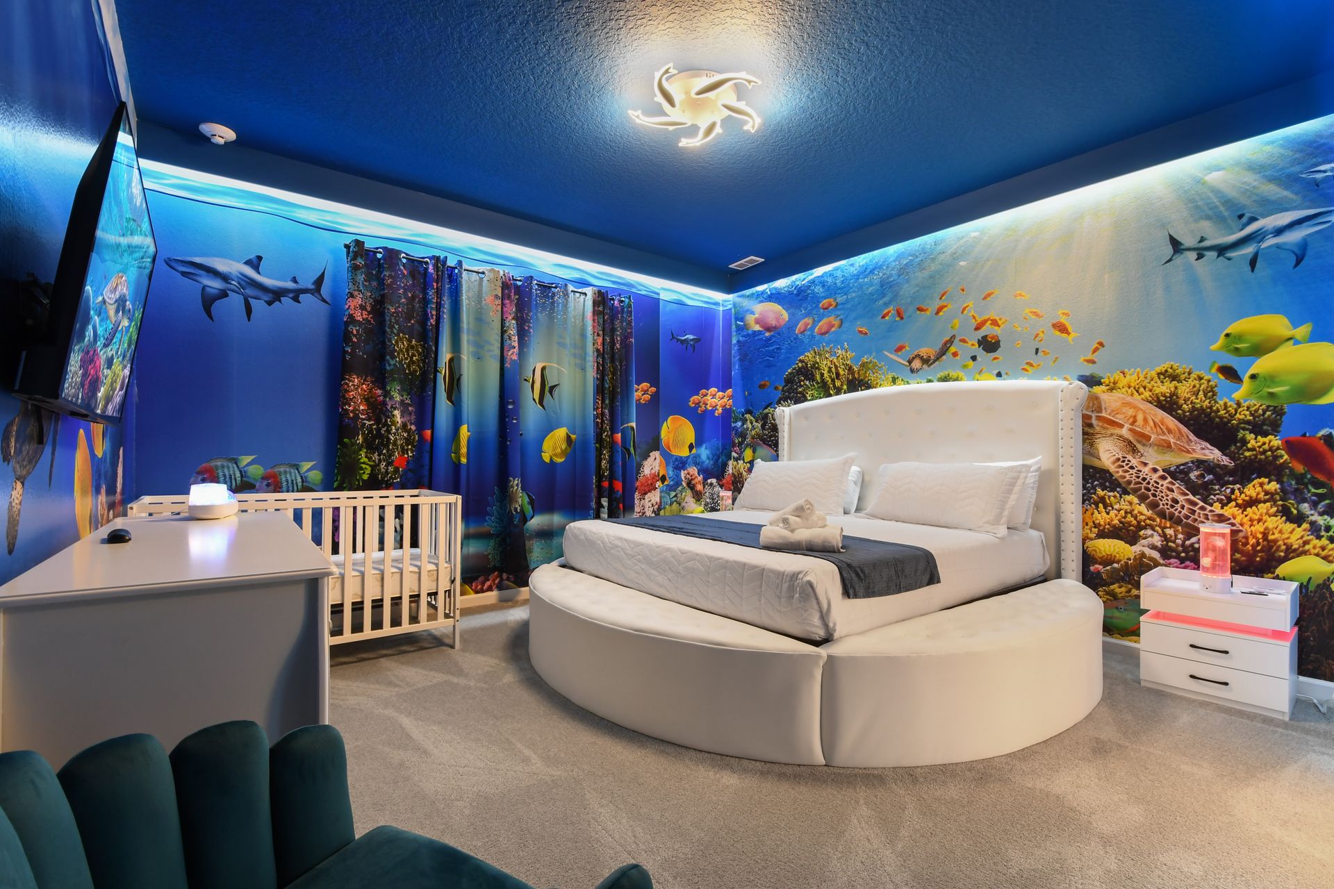 Underwater-themed master with round bed, ocean murals, and cozy crib setup
