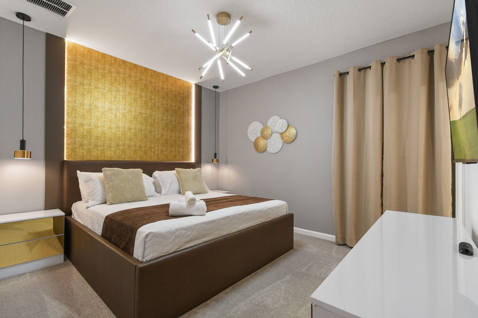 Modern bedroom with gold accents, plush king bed, and striking statement lighting
