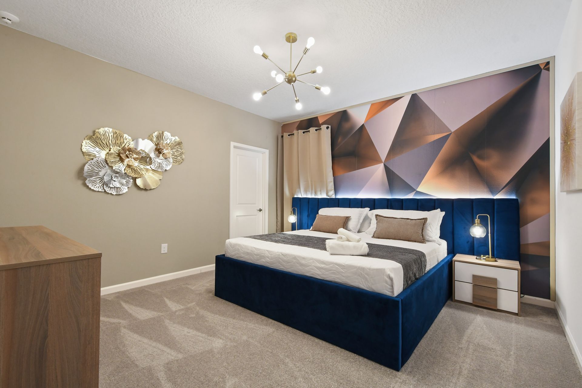 Contemporary bedroom with bold geometric wall, plush bed, and luxe lighting touches
