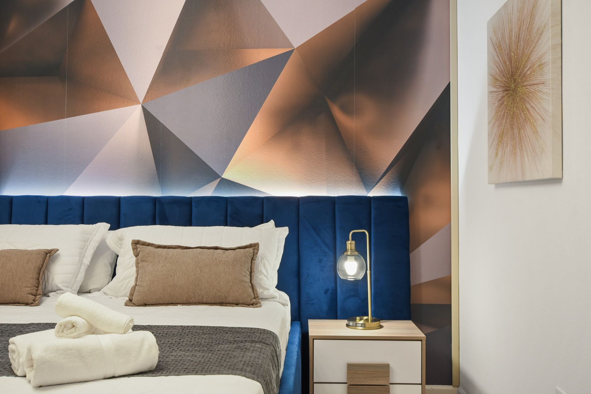 Contemporary bedroom with bold geometric wall, plush bed, and luxe lighting touches
