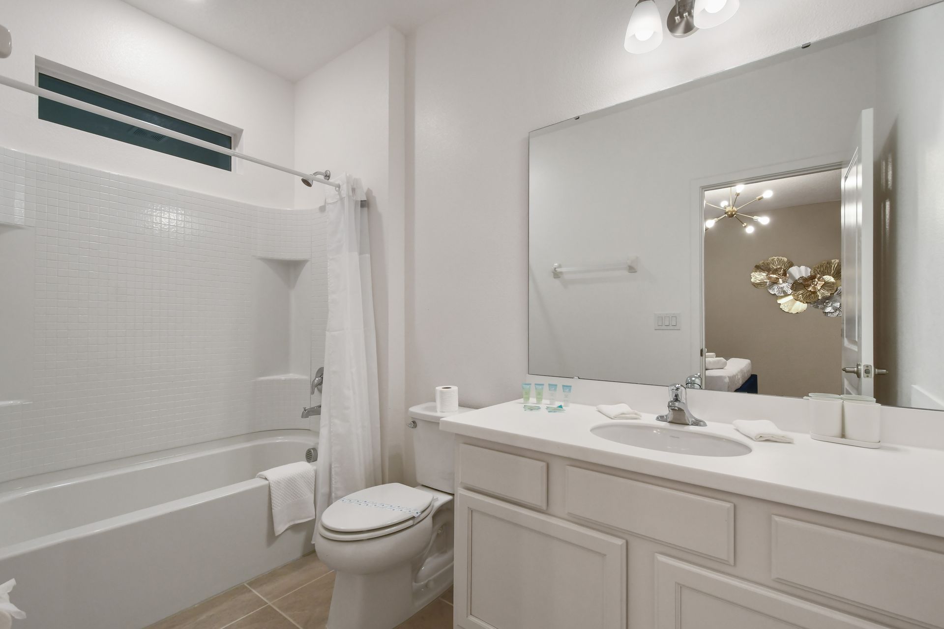 Modern ensuite bathroom with clean white finishes, full tub-shower, and large vanity
