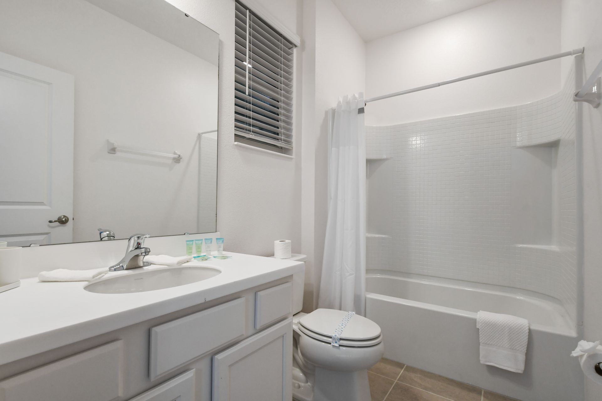 Sleek guest bathroom with bright white finishes, full tub, and spacious vanity
