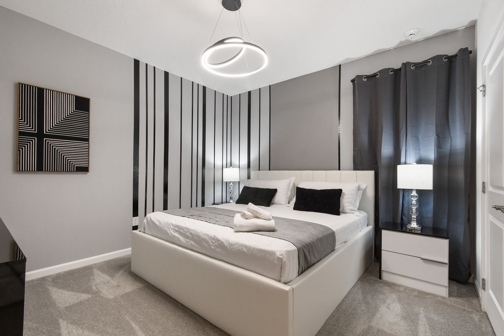 Chic monochrome bedroom with modern lighting, sleek decor, and cozy king bed
