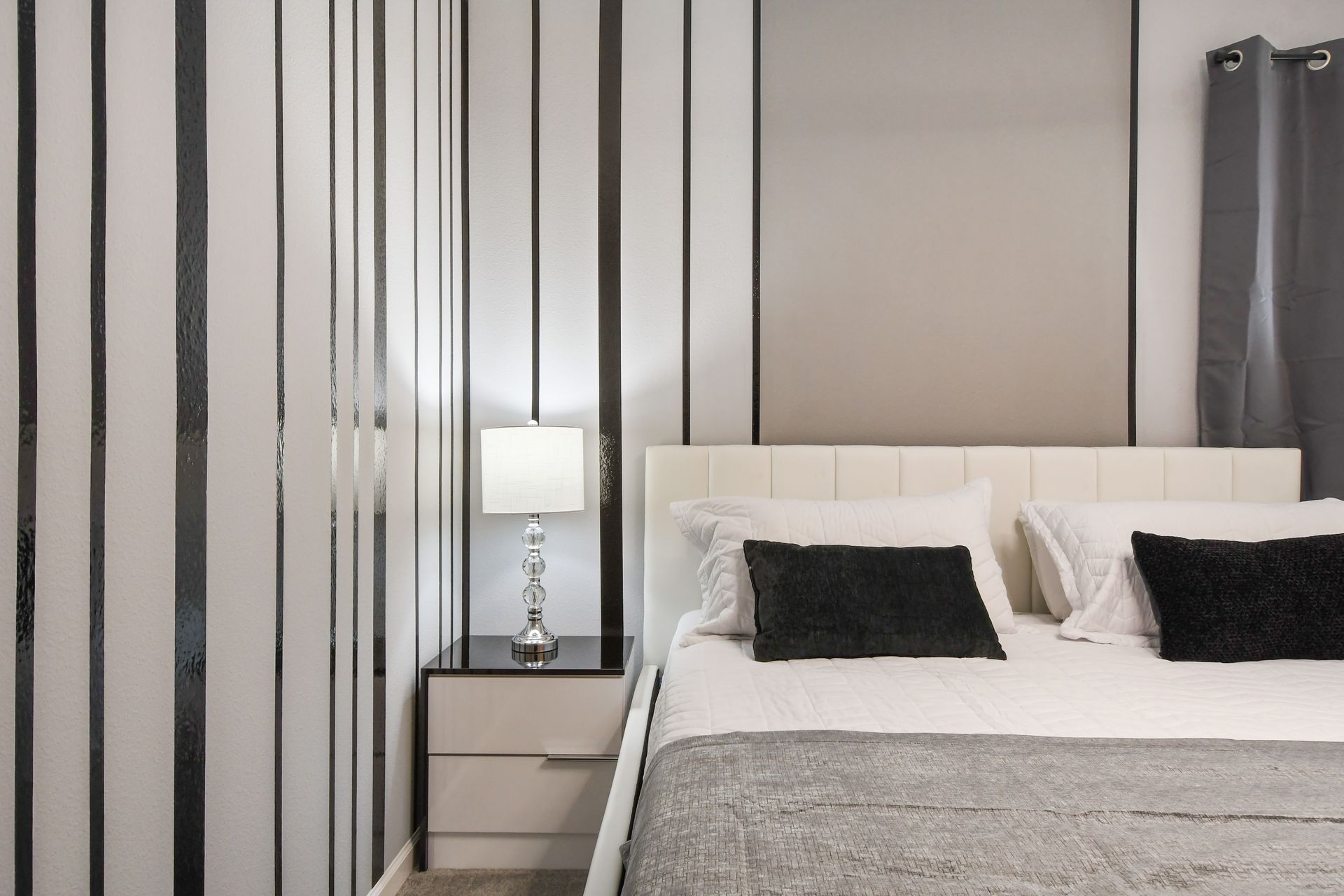 Chic monochrome bedroom with modern lighting, sleek decor, and cozy king bed
