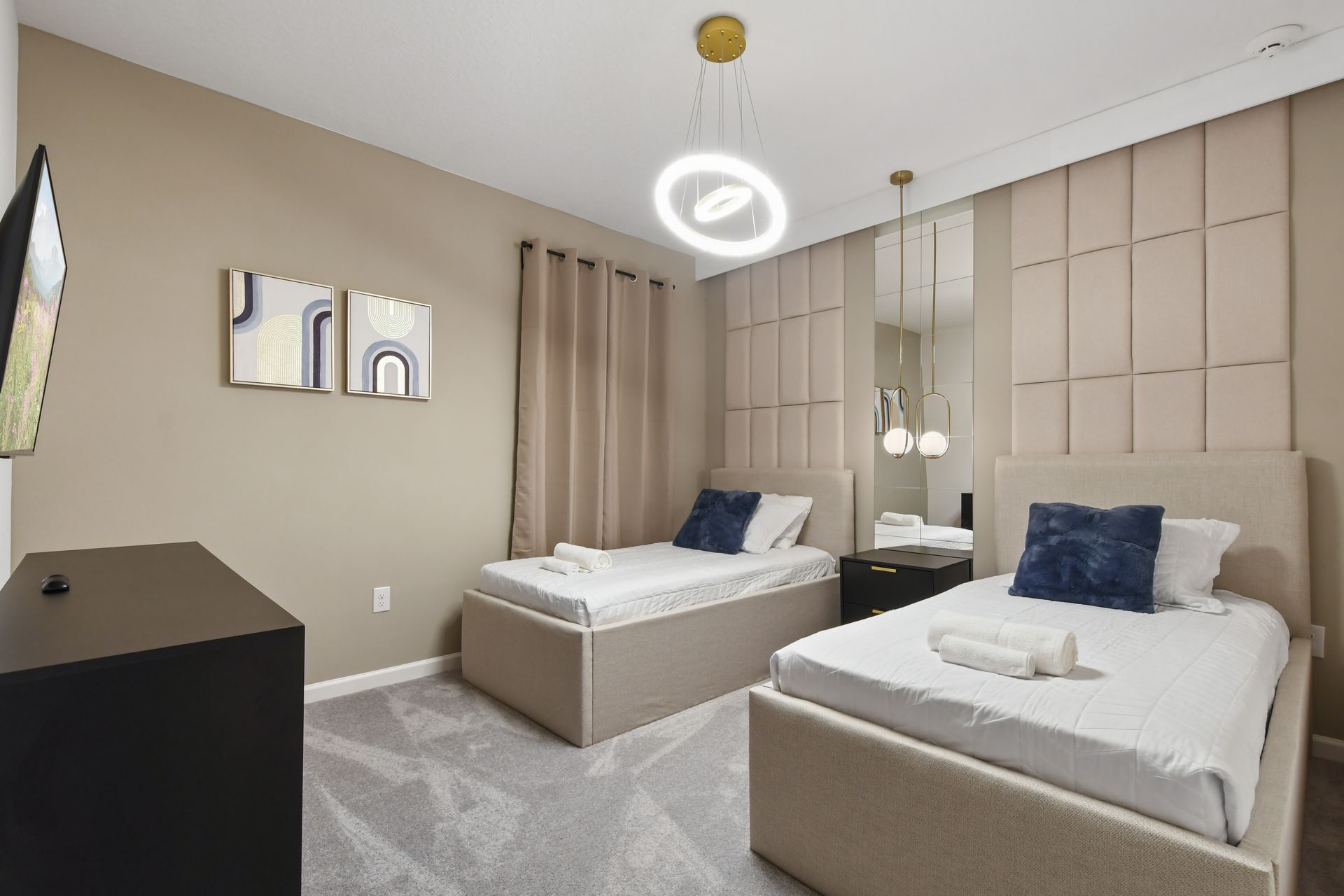 Elegant twin bedroom with plush headboards, modern lighting, and cozy neutral tones
