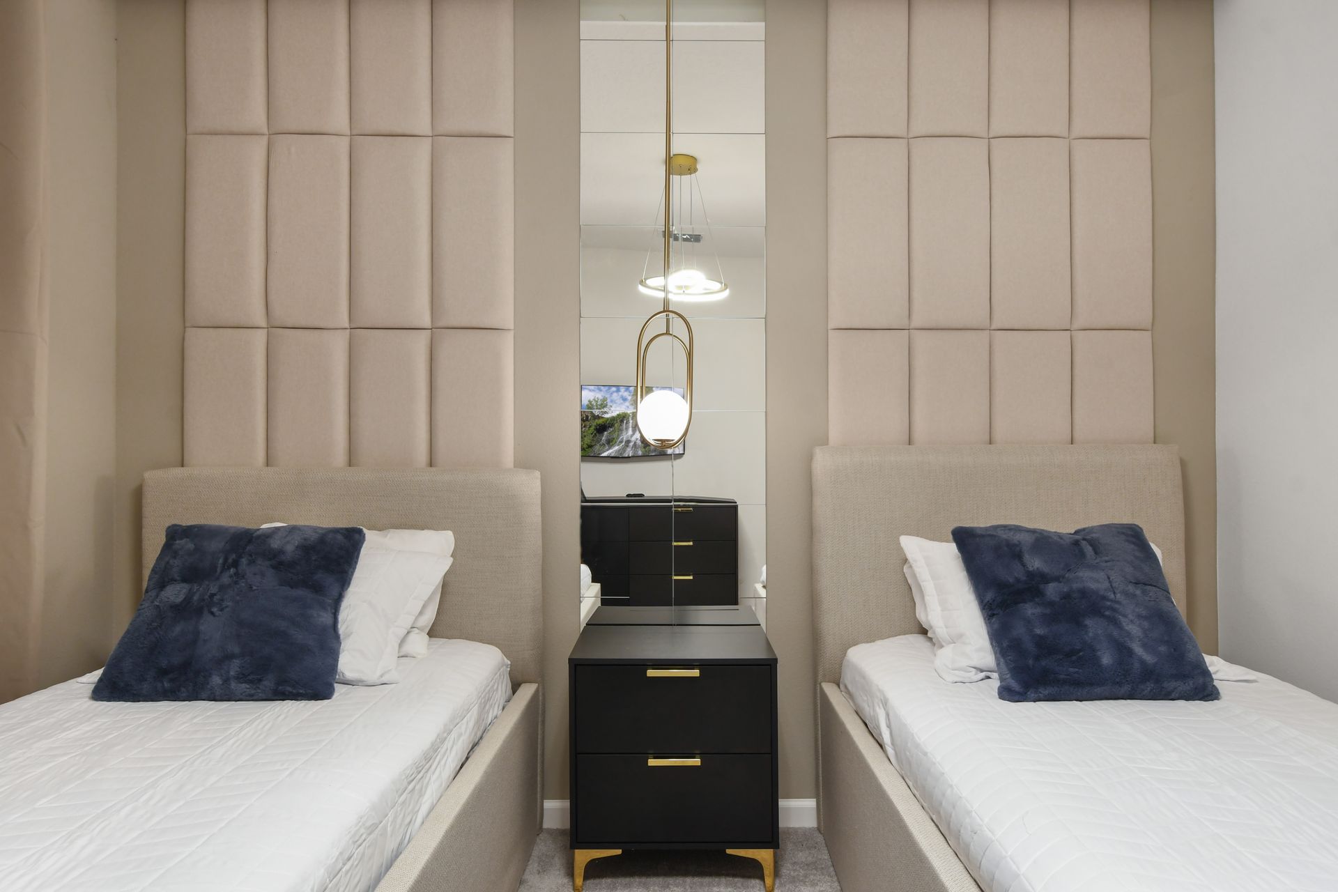 Elegant twin bedroom with plush headboards, modern lighting, and cozy neutral tones
