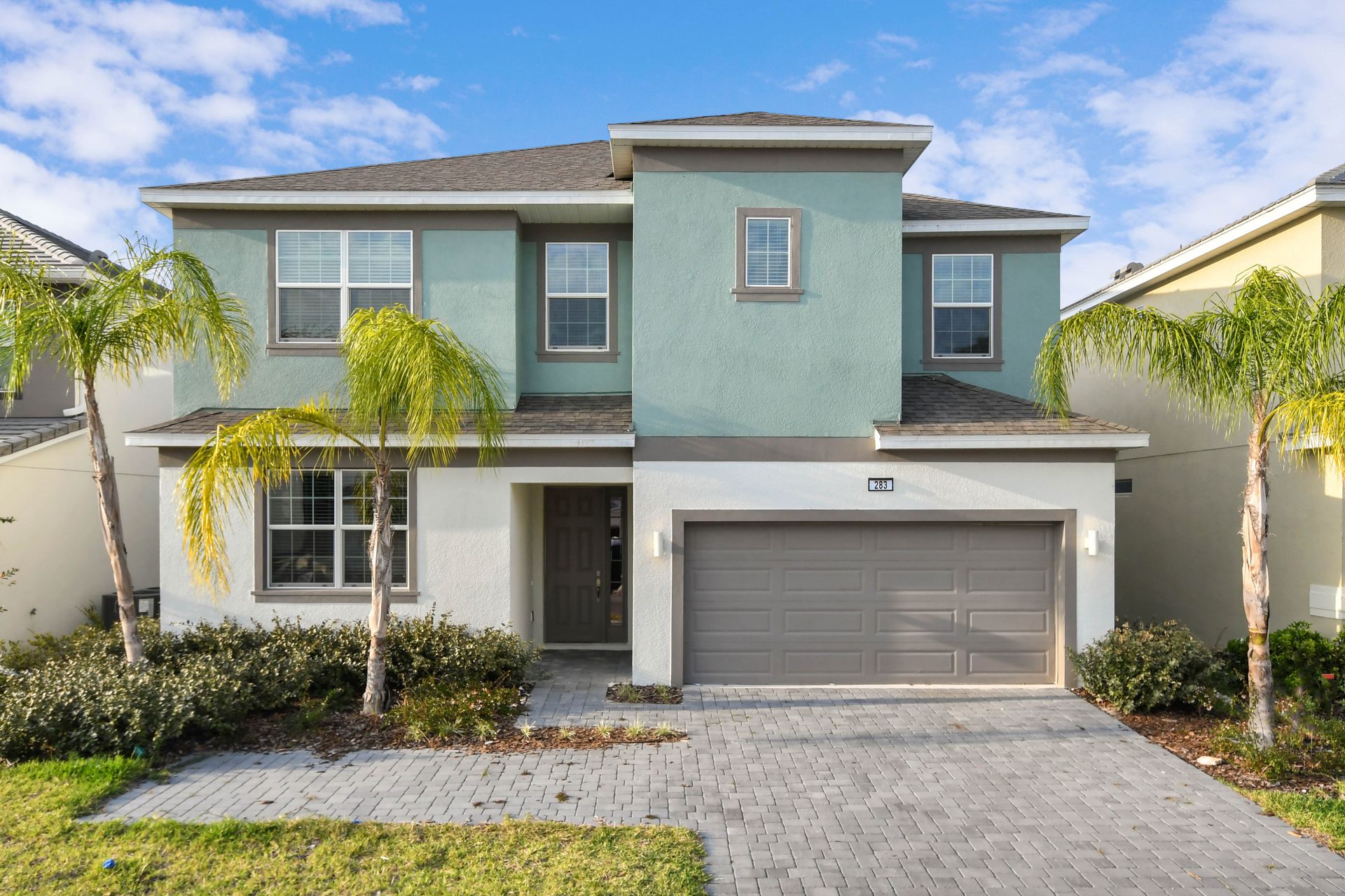 Spacious modern home with palm trees, a two-car garage, and a welcoming entry.
