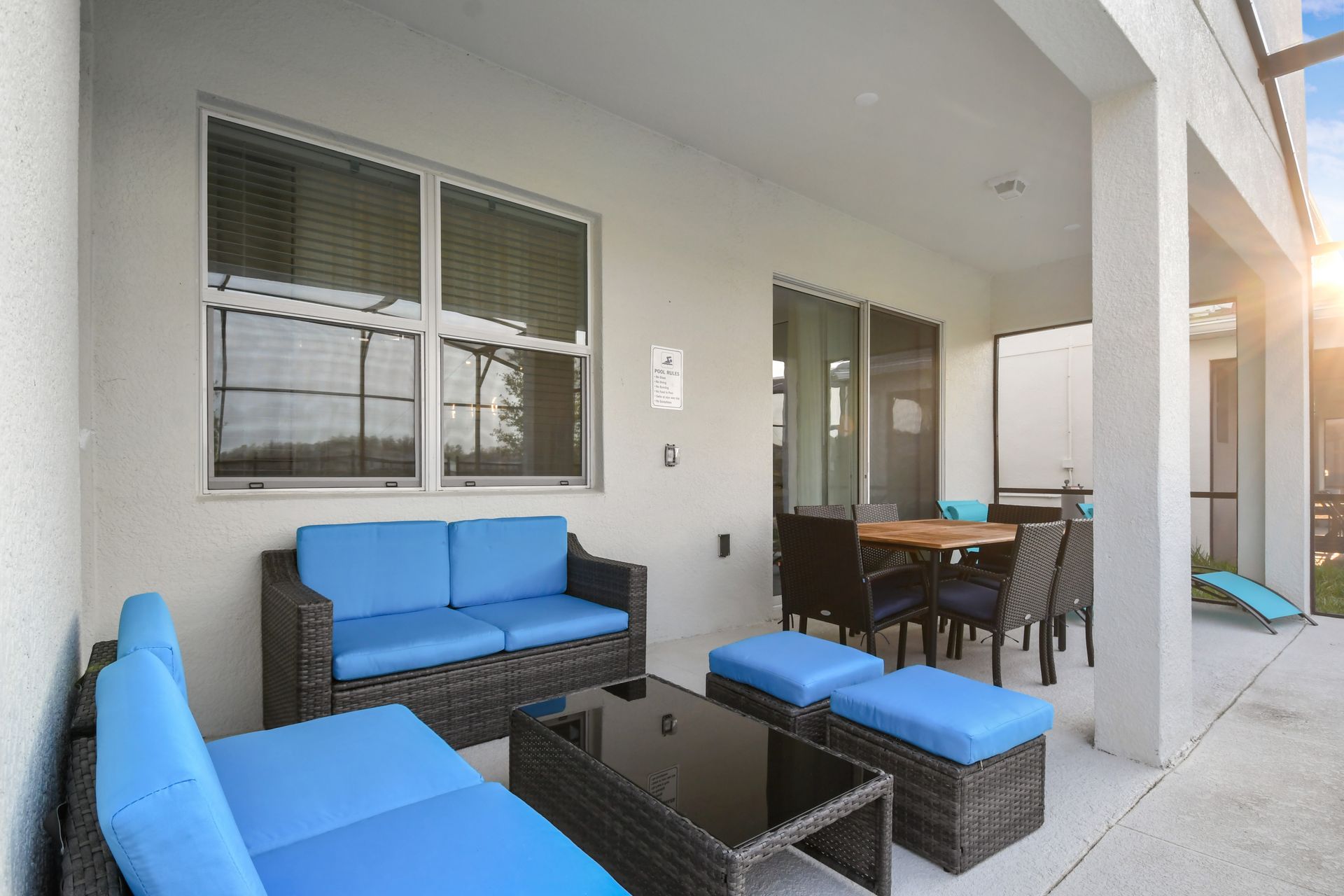 Relax on the covered patio with cozy seating and a dining area by the pool.