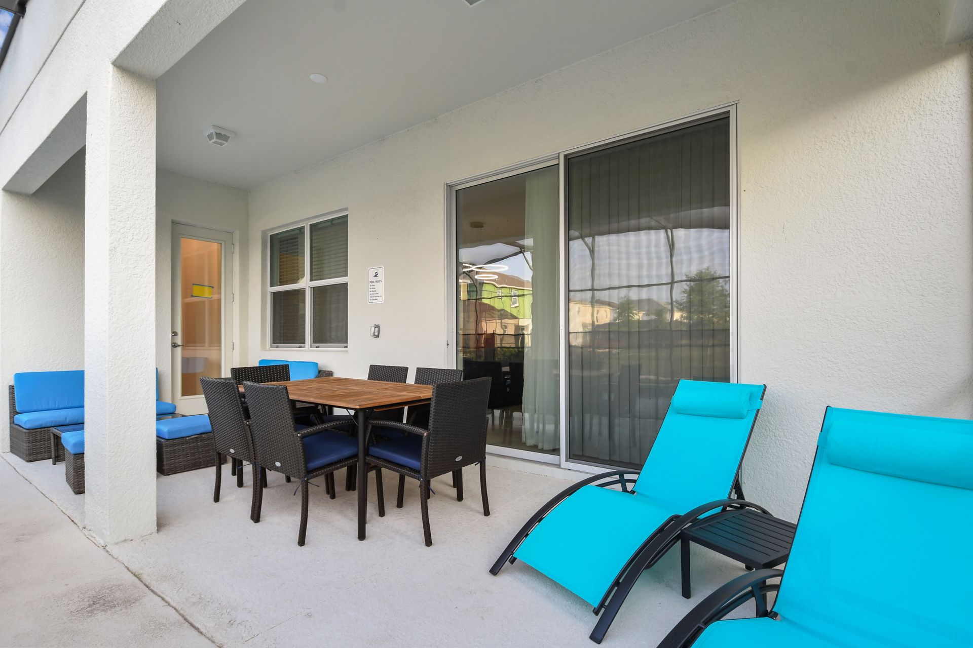 Relax on the covered patio with cozy seating and a dining area by the pool.