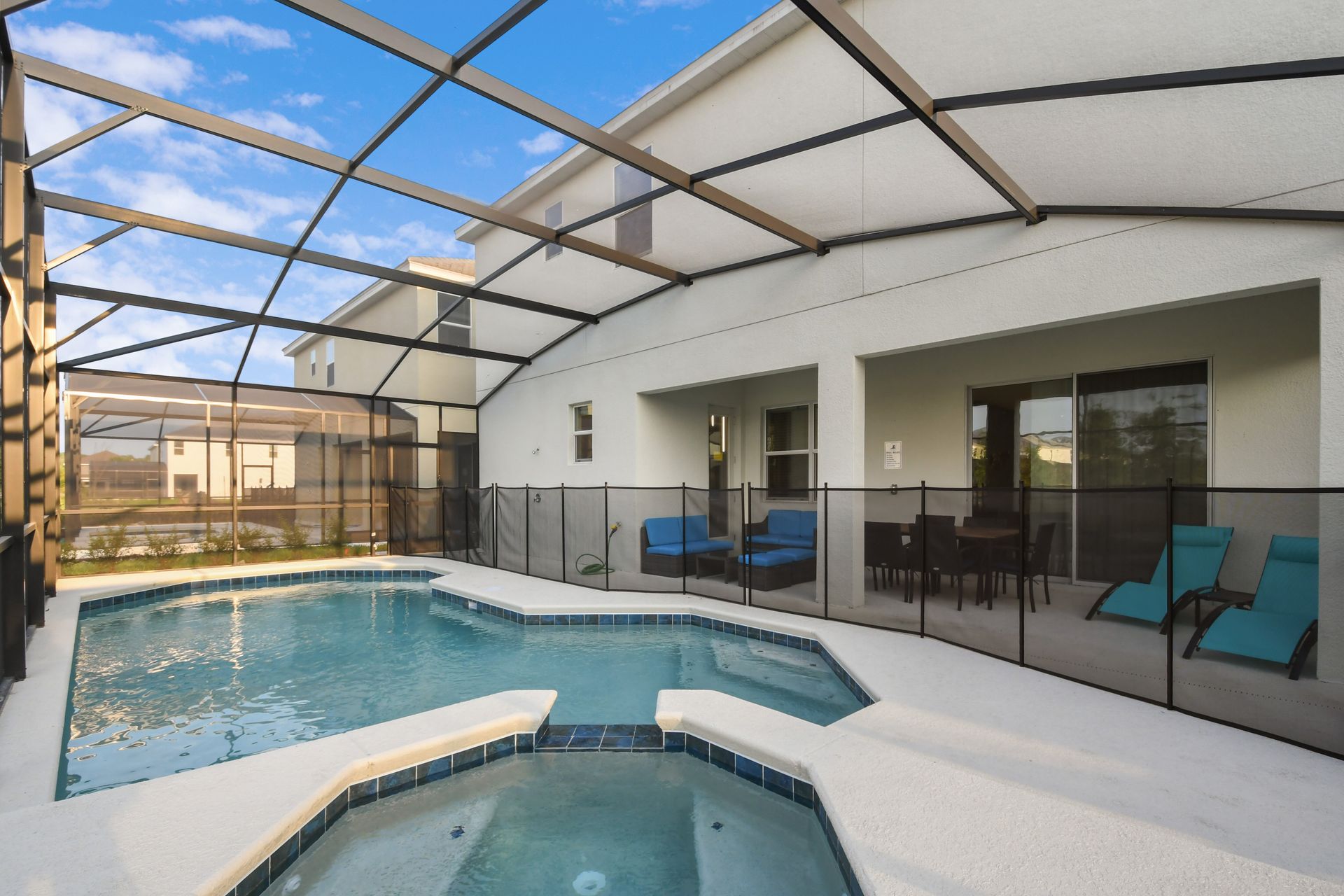 Spacious screened-in pool area with spa, lounge chairs, and outdoor seating.
