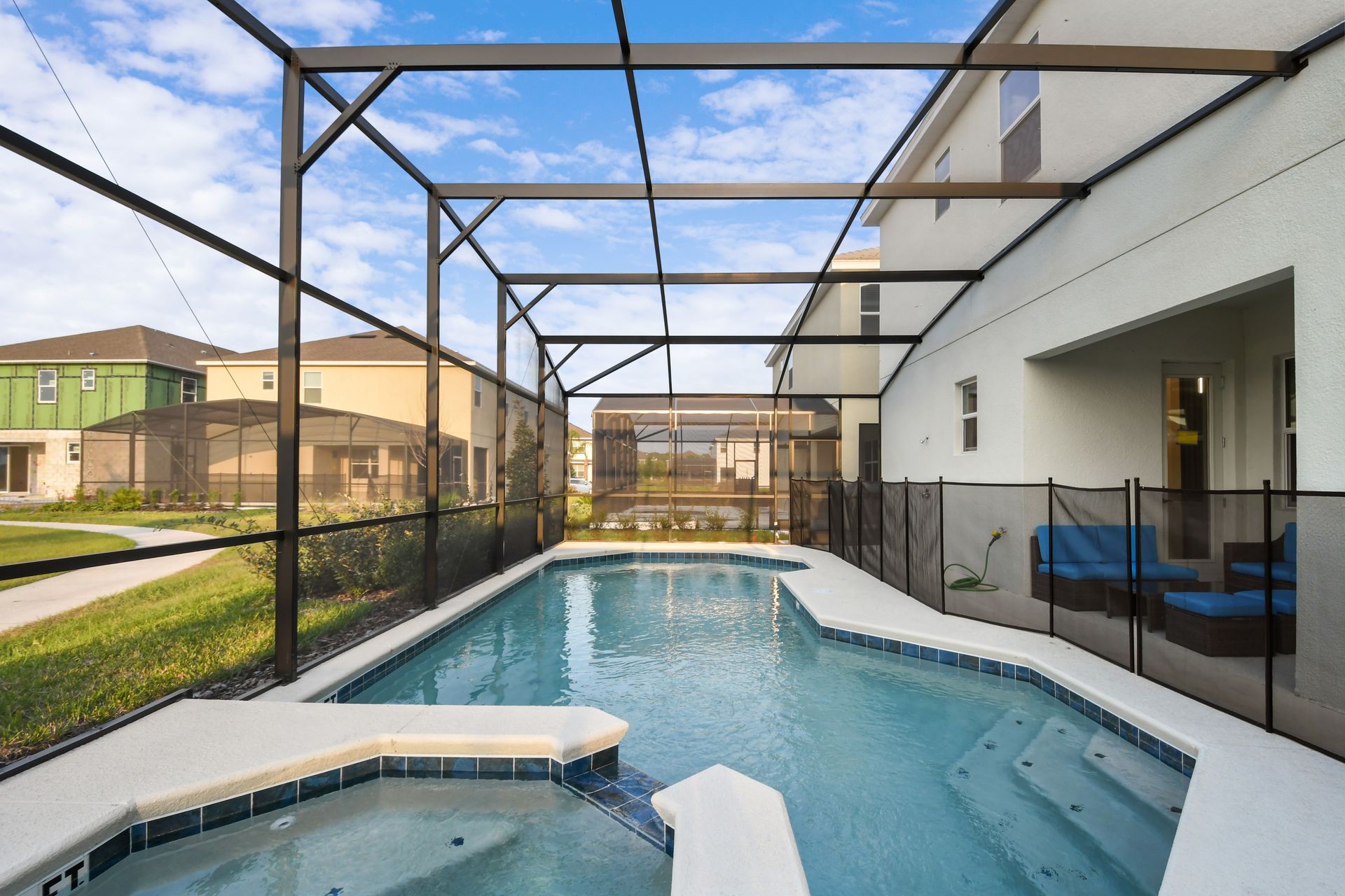 Screened-in pool with spa overlooking a serene lake and lush greenery.