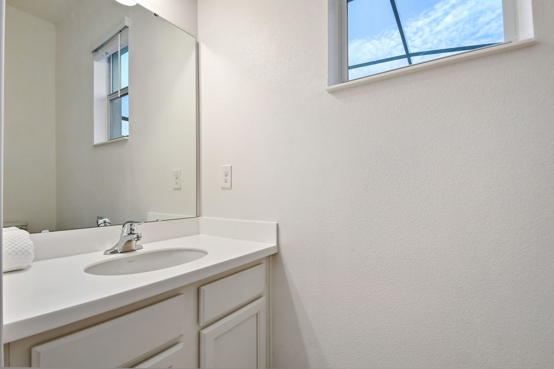 Bright and simple bathroom with natural light and a clean white vanity.