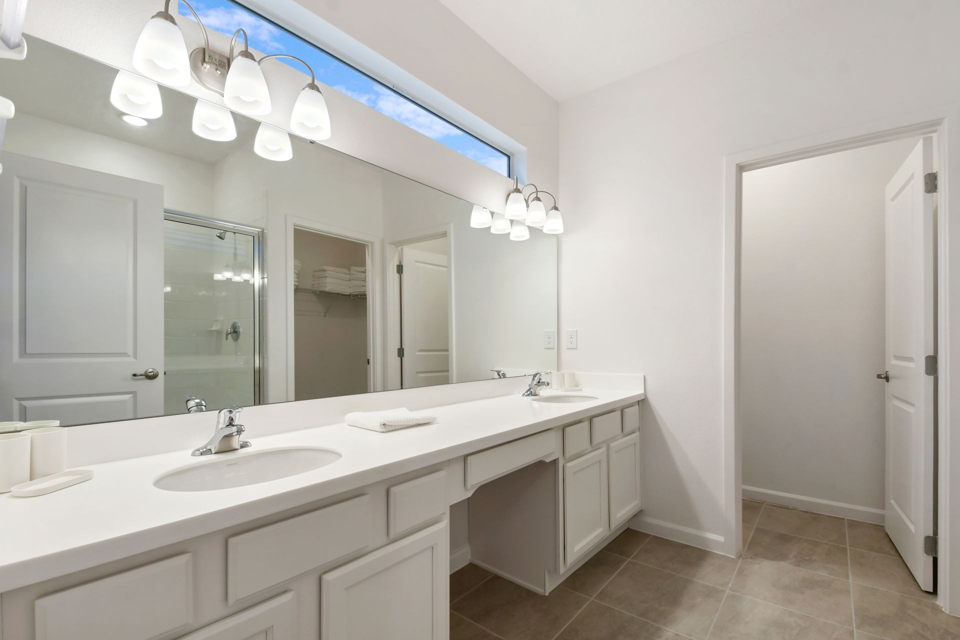Spacious bathroom with double vanity, bright lighting, and modern fixtures.