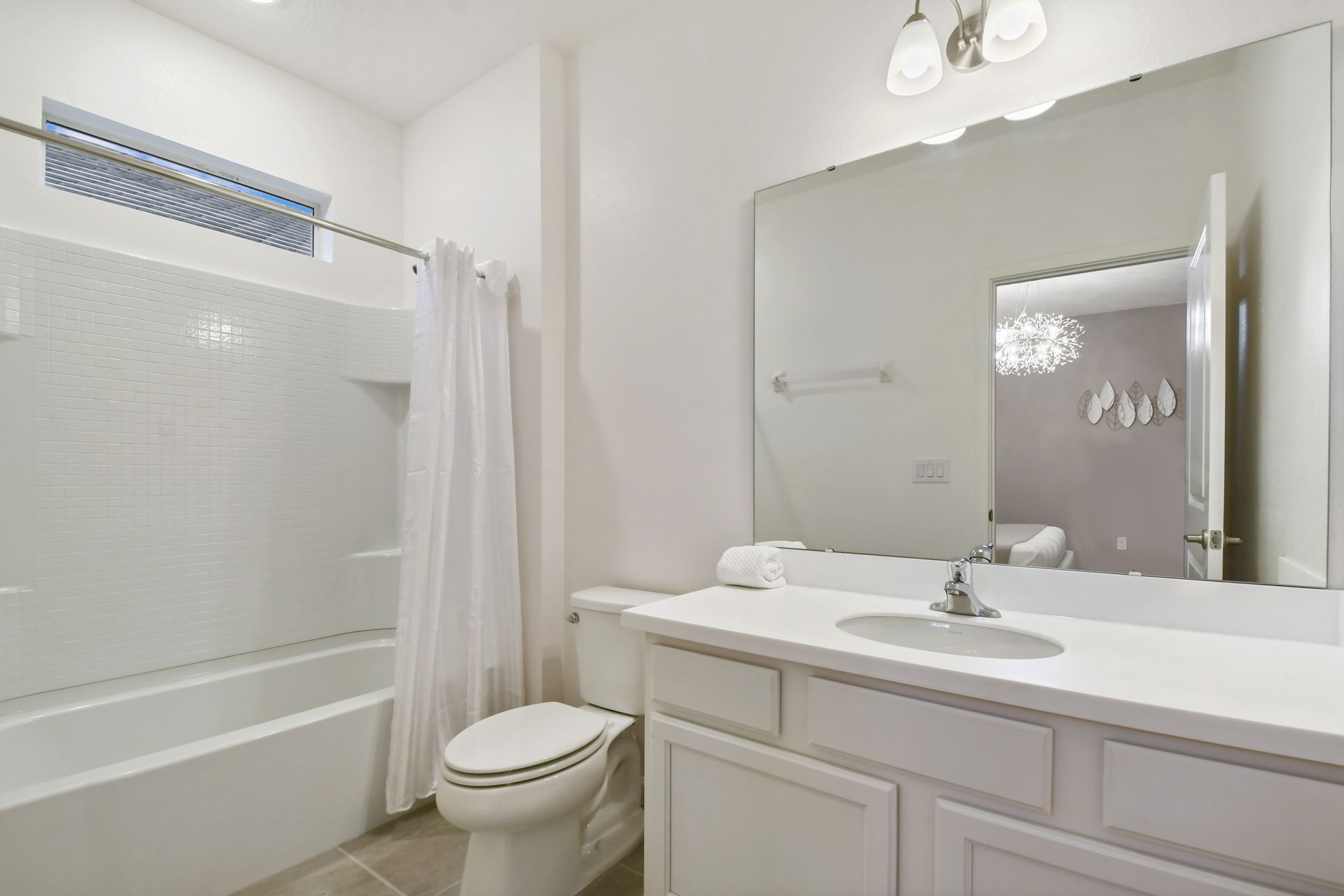 Bright and clean bathroom with a large mirror and a full shower-tub combo.