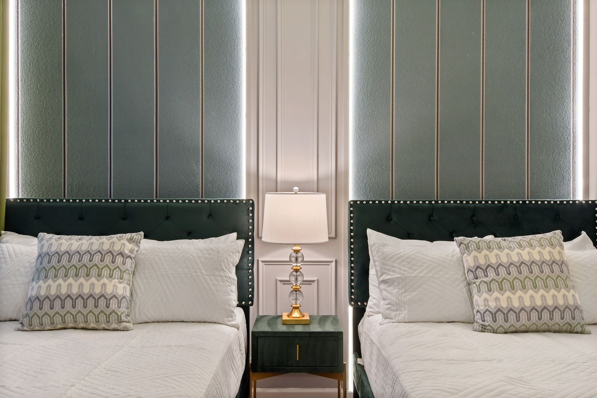 Chic room with twin beds, elegant lighting, and sophisticated green accents.