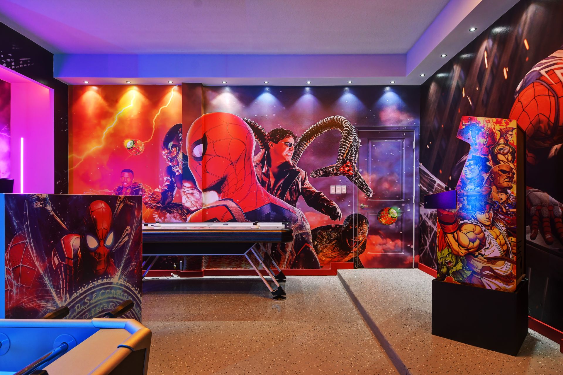 Spiderman-themed gaming station with dual monitors, neon lights, and foosball.