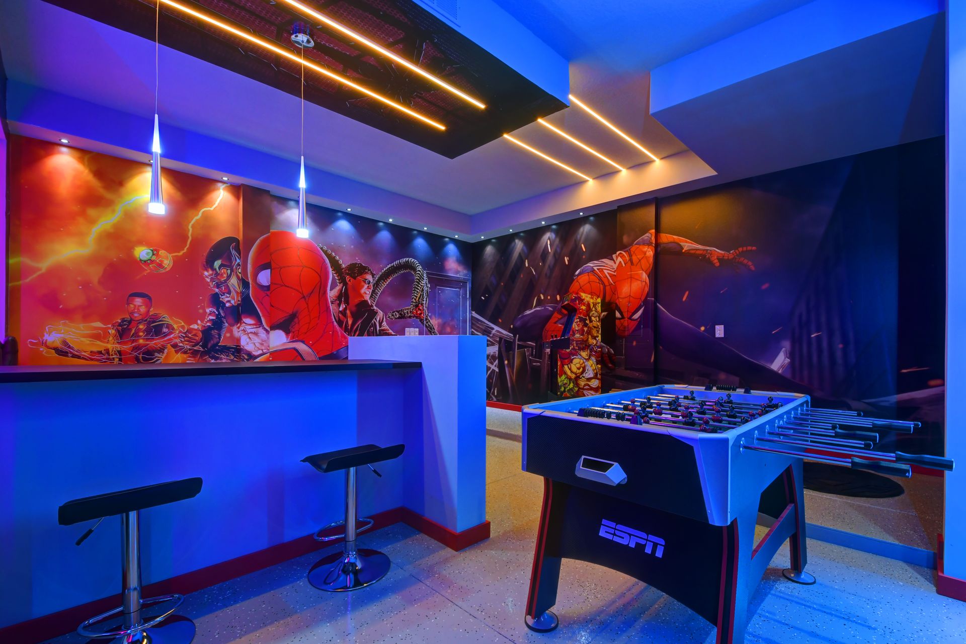 Spiderman-themed gaming station with dual monitors, neon lights, and foosball.