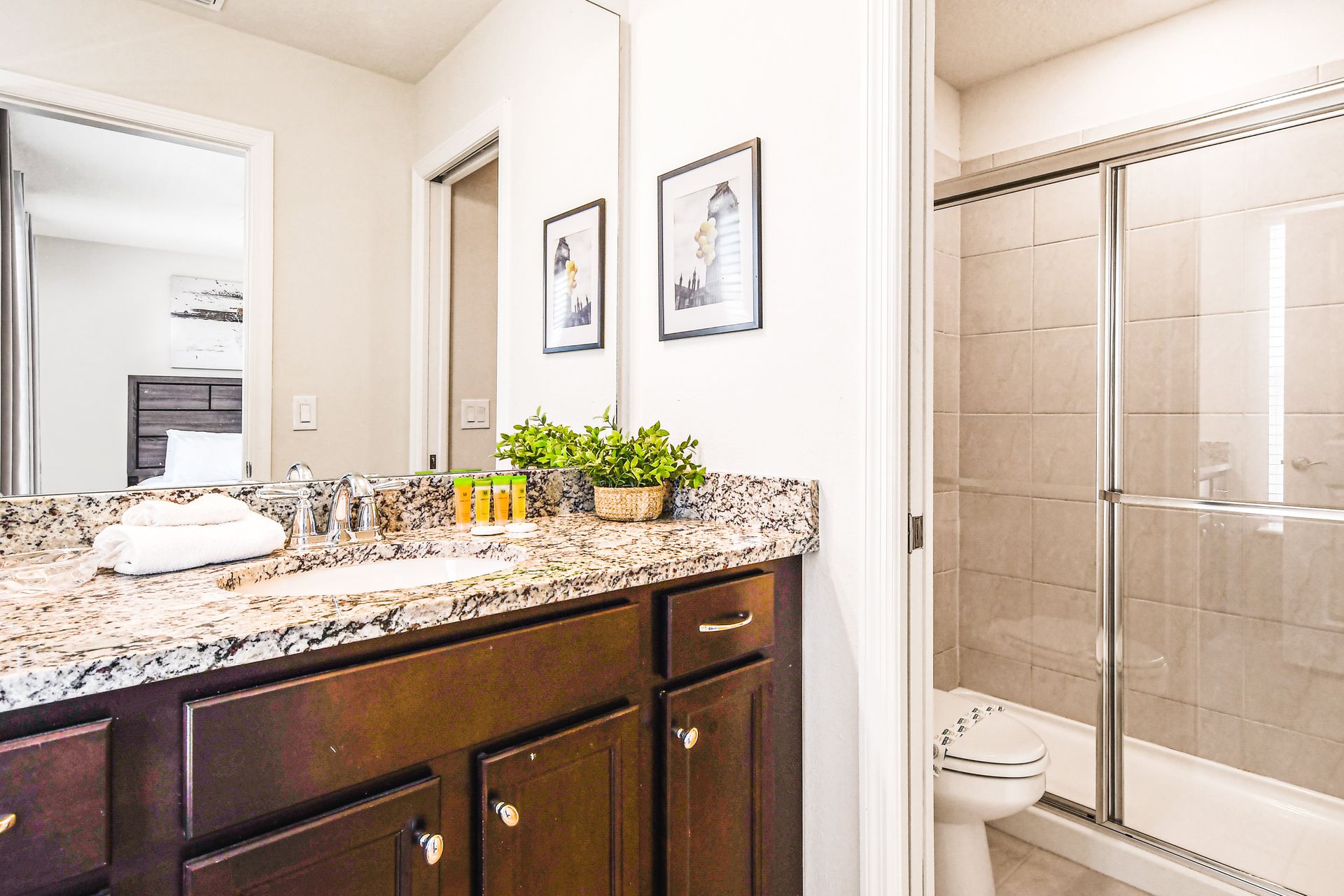 Cozy bathroom with granite counters, bright decor, and glass shower.