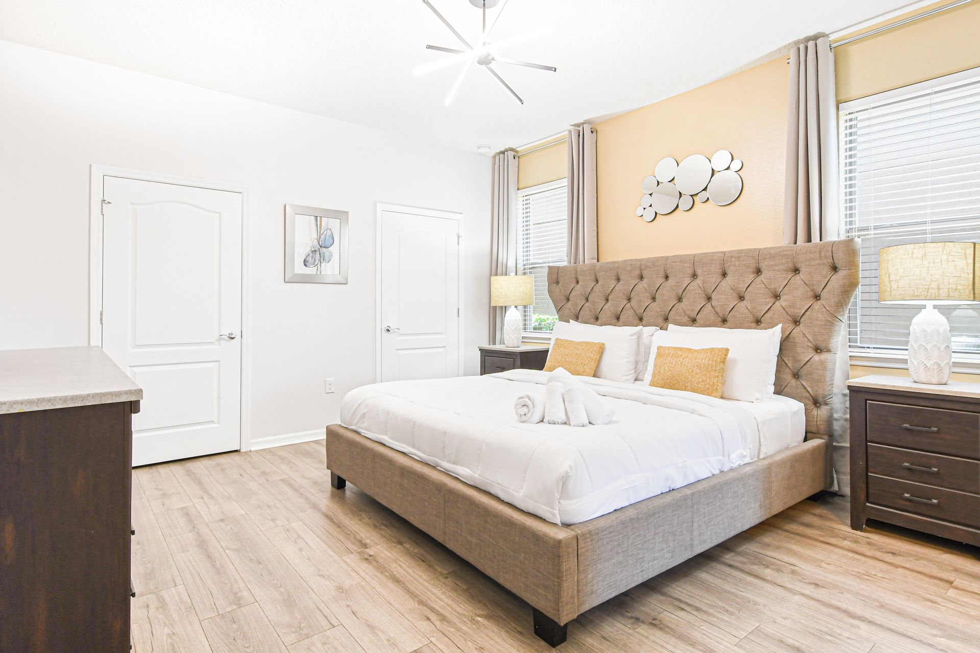 Elegant king bedroom with stylish lighting, warm tones, and natural light views.