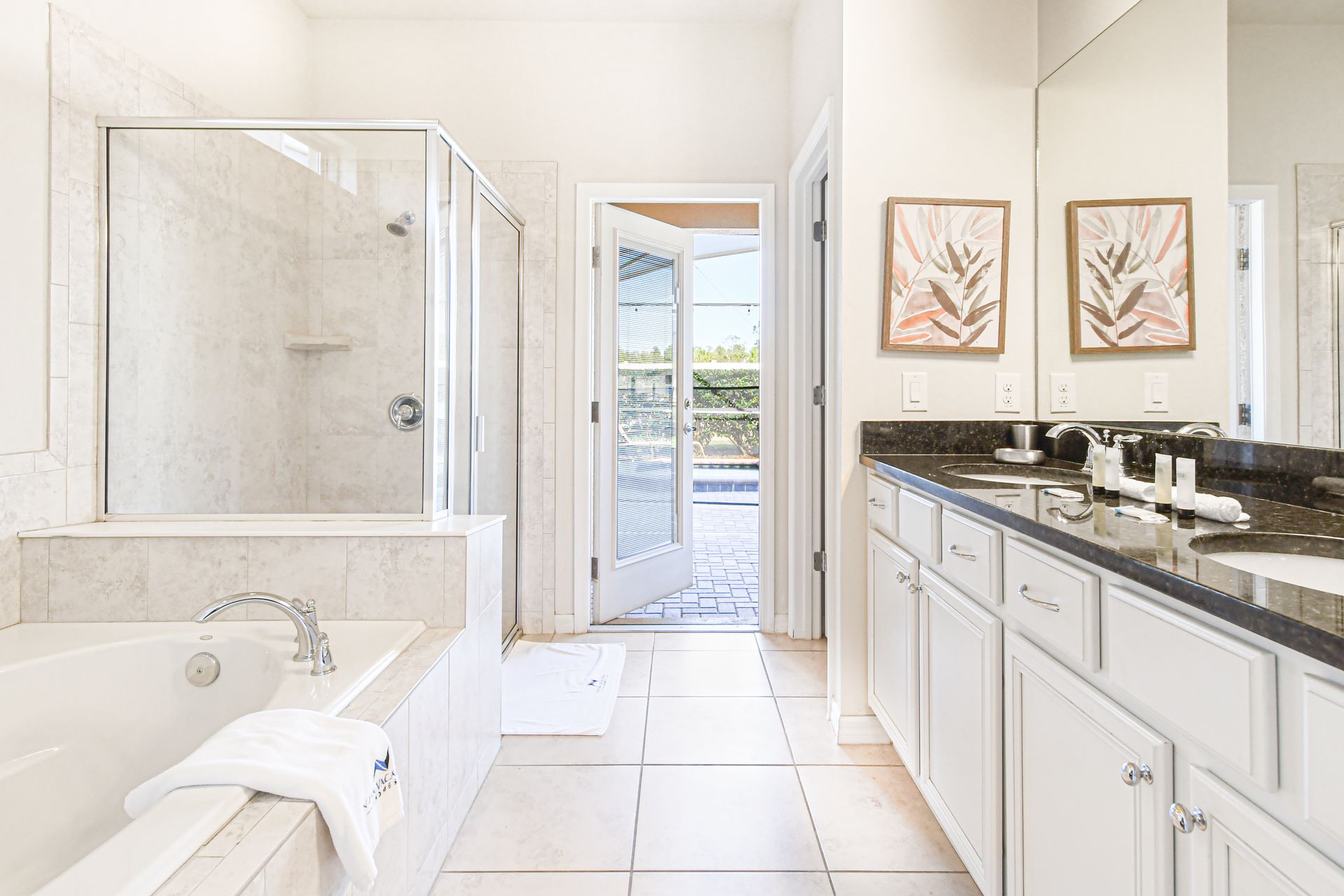 Spacious bath with soaking tub, dual vanities, walk-in shower, and poolside access.