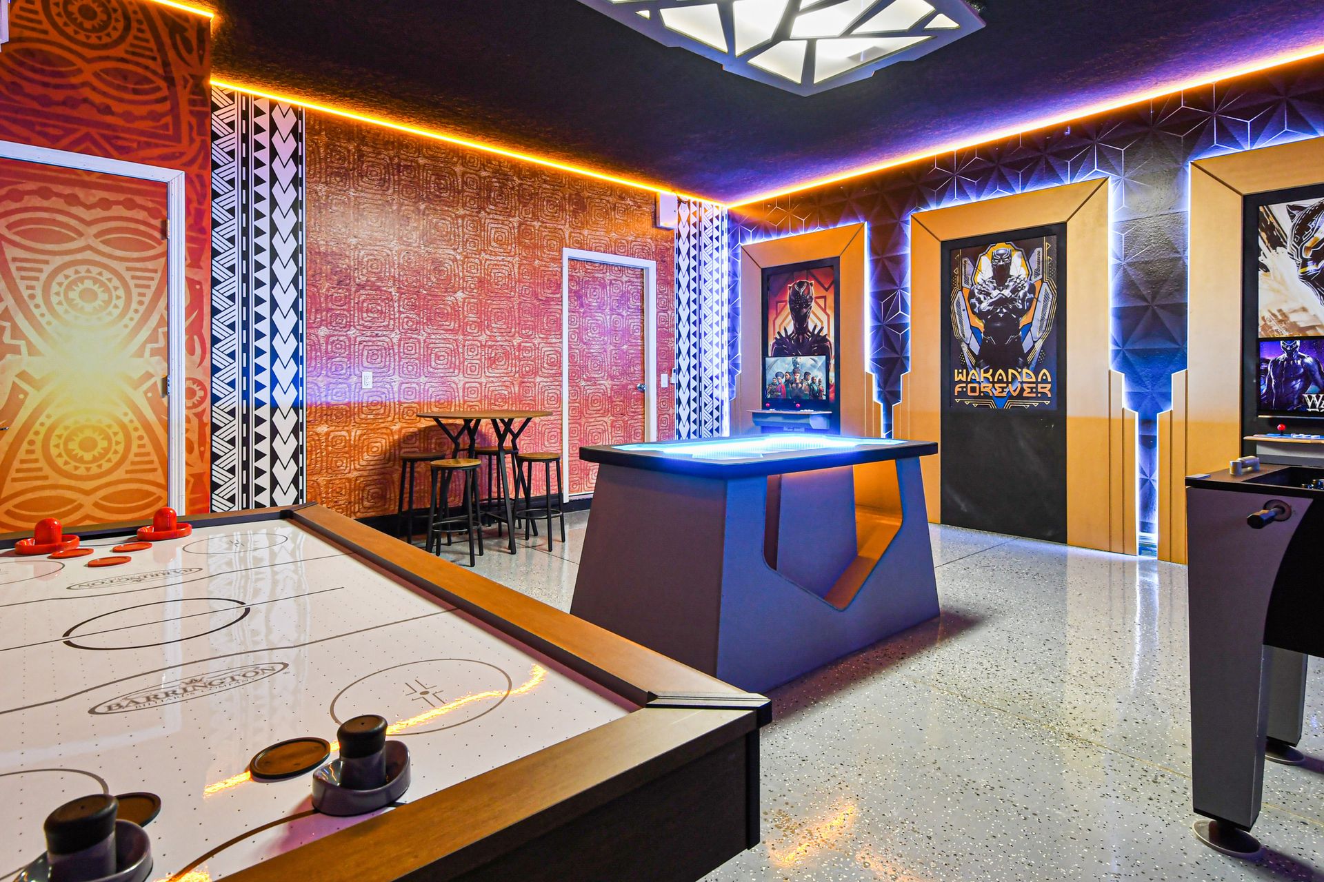 Wakanda-themed game room with air hockey, arcade, and custom lighting design.