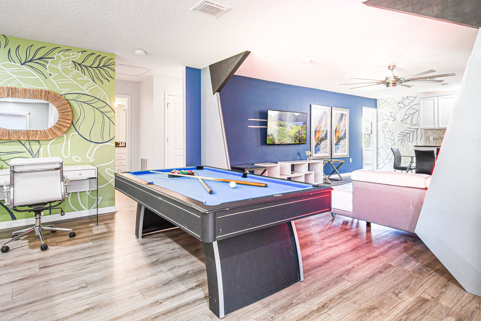 Bright loft space with pool table, desk, bold colors, and tropical wall art.
