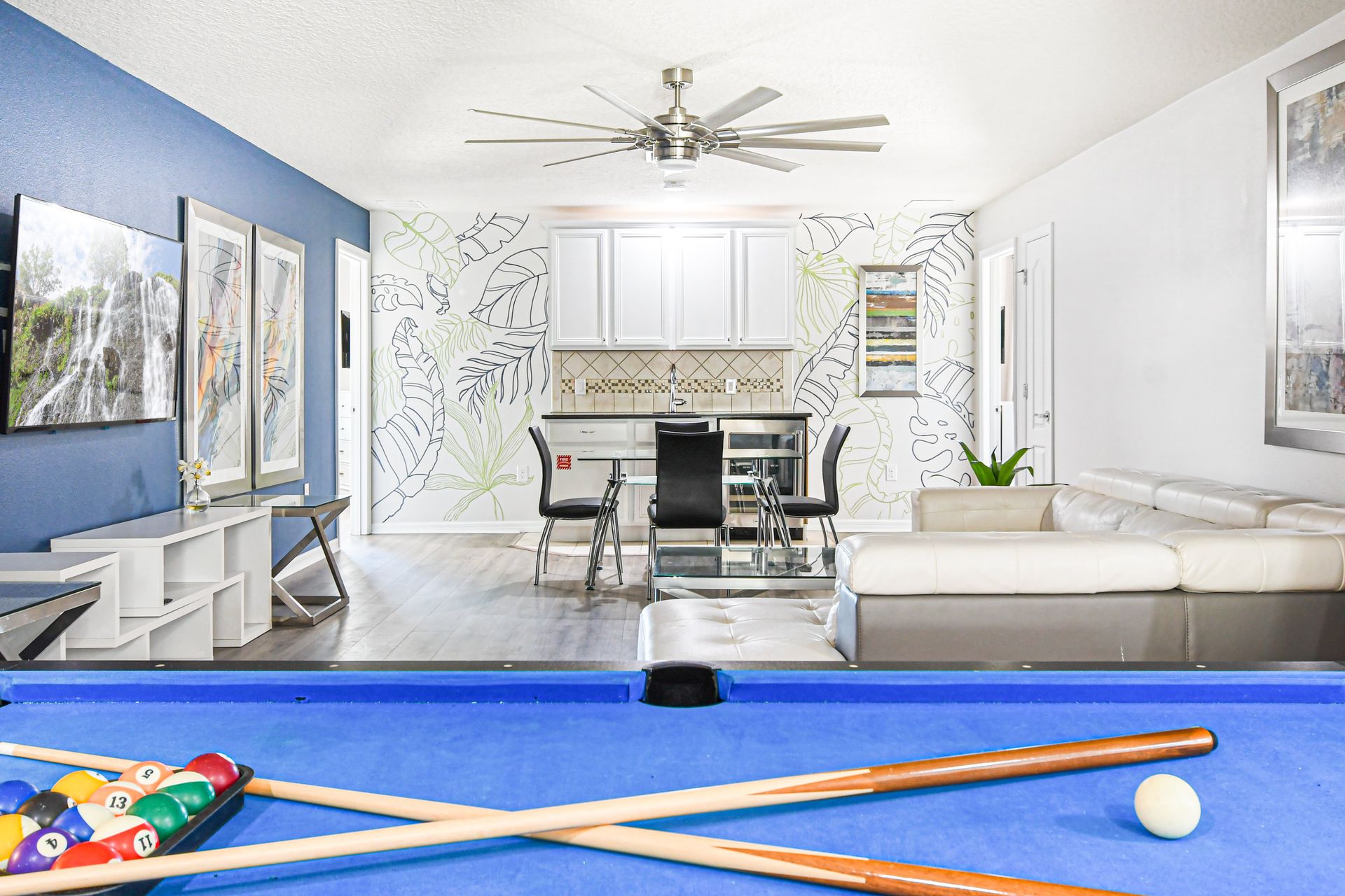 Colorful loft with pool table, TV, modern art, and tropical wall accents.