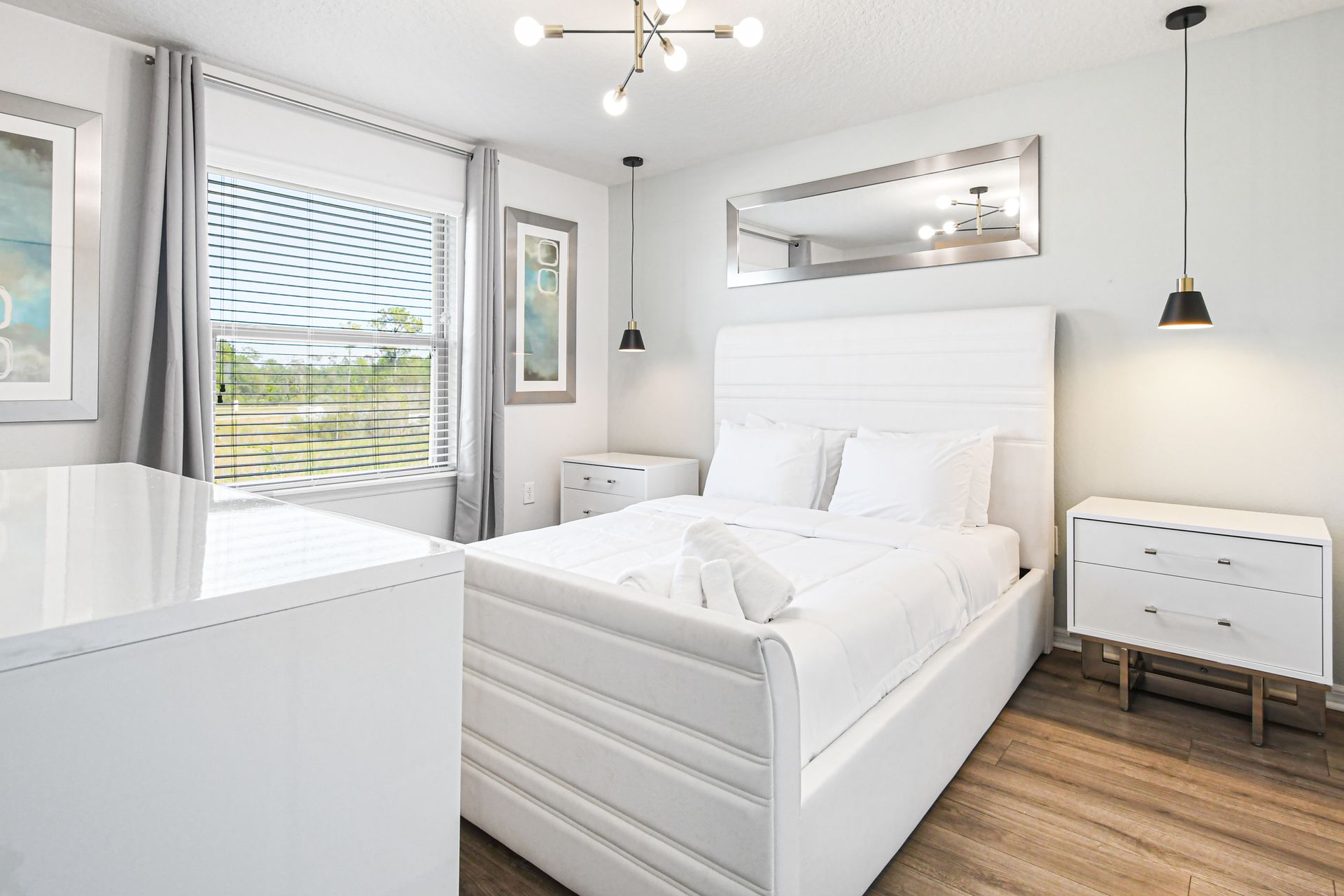 Chic, serene bedroom with plush queen bed, modern lighting, and nature views.