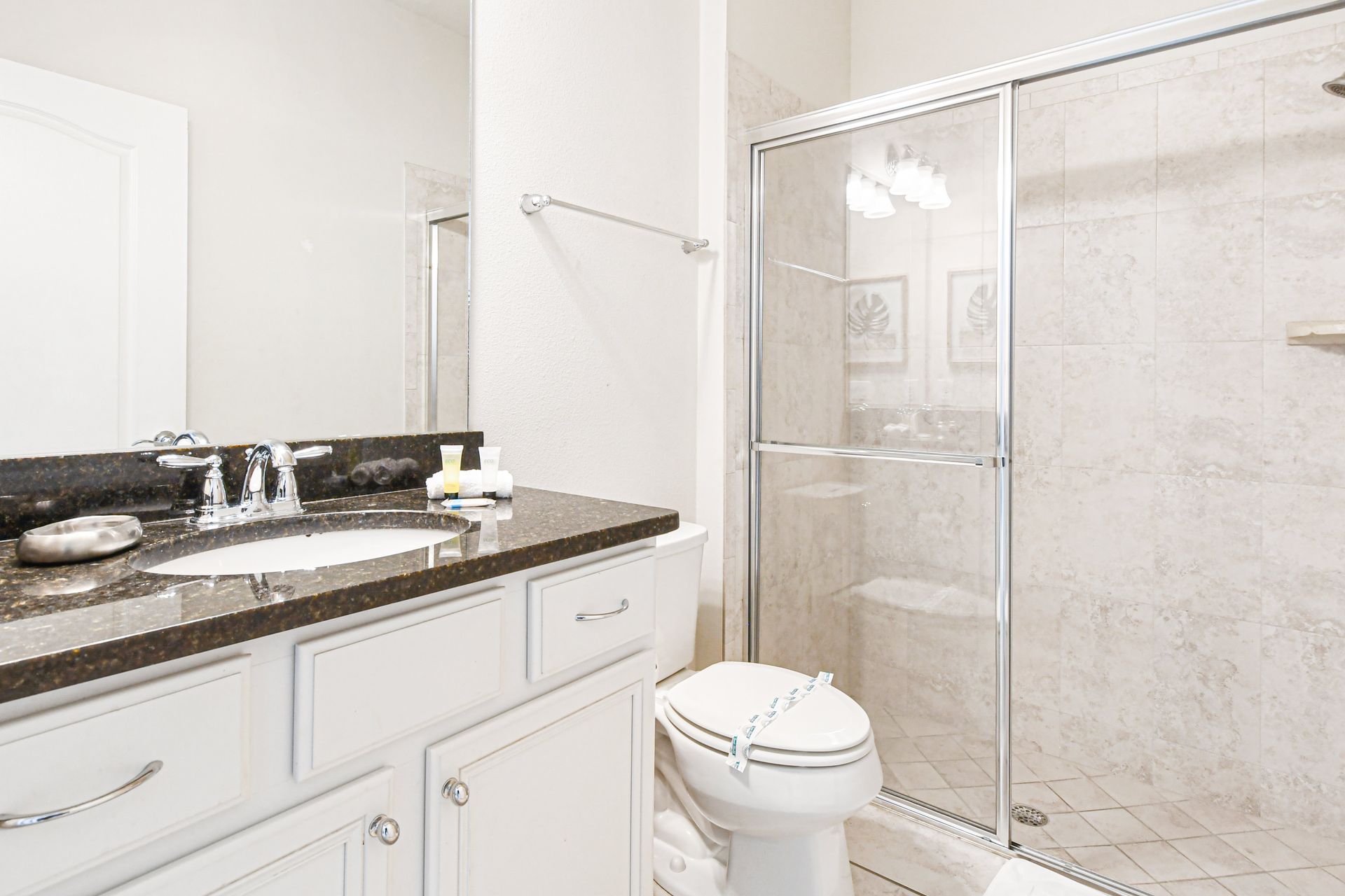 Elegant bathroom with granite vanity, glass shower, and bright, clean design.