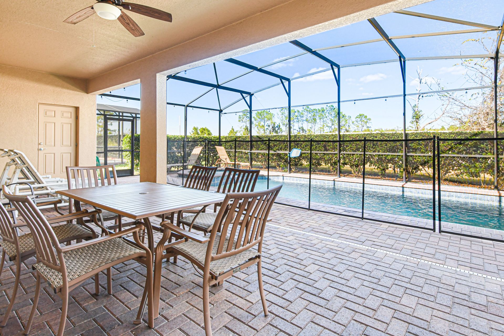 Spacious lanai with dining table, lounge seating, and views of private screened pool.