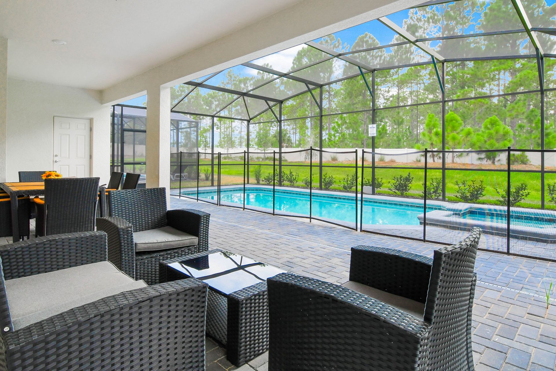 Covered patio with outdoor dining, lounge seating, and screened-in pool and spa.