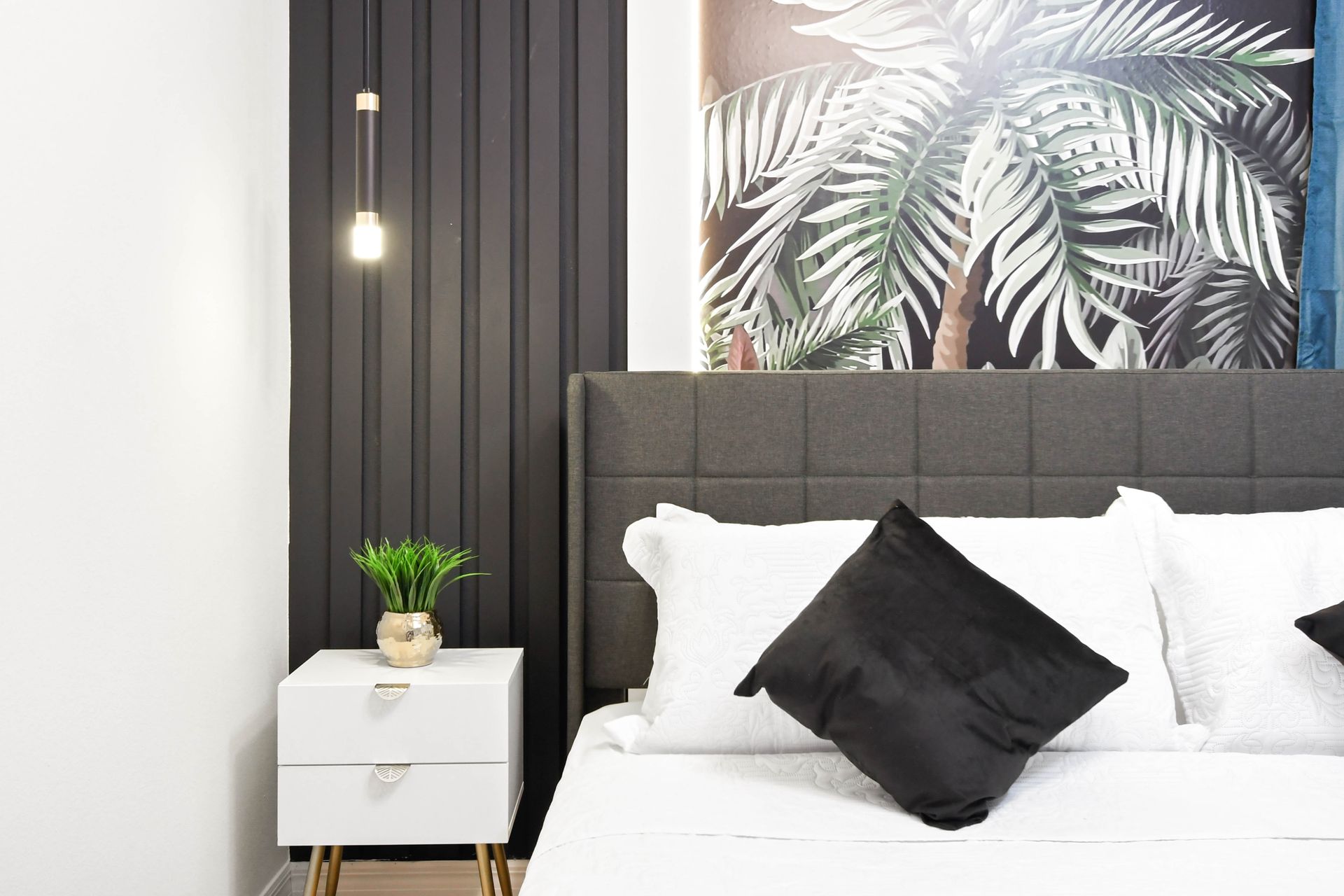 Close-up of a sleek modern bedroom with tropical accent wall and elegant lighting.