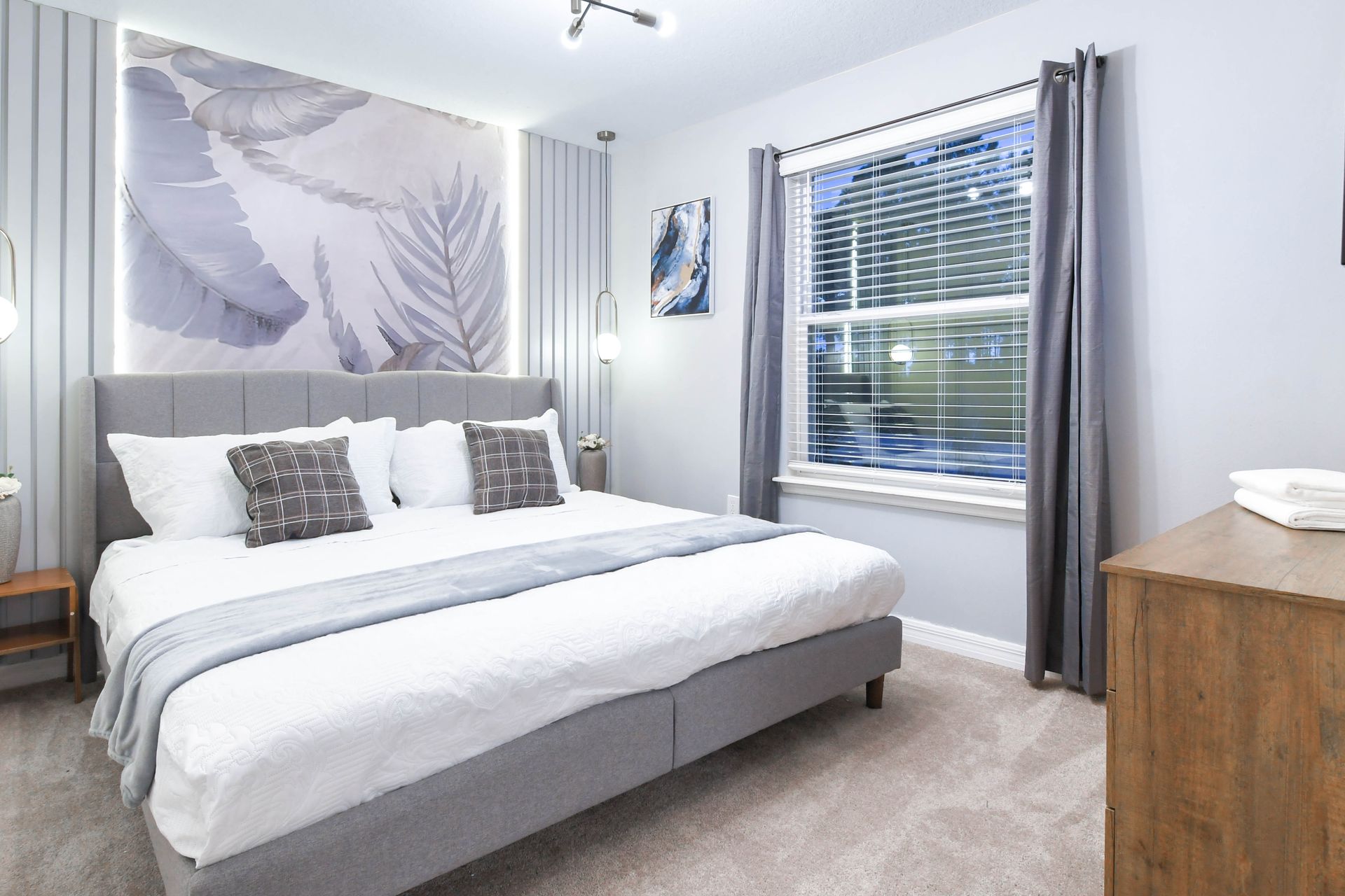Serene gray-toned bedroom with king bed, soft lighting, and modern botanical art.