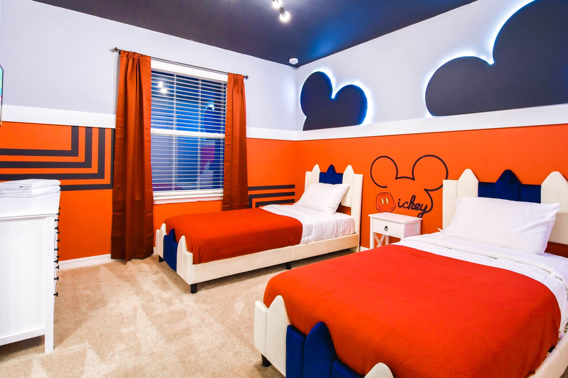 Mickey-themed kids’ room with twin beds, bold colors, and playful wall designs.