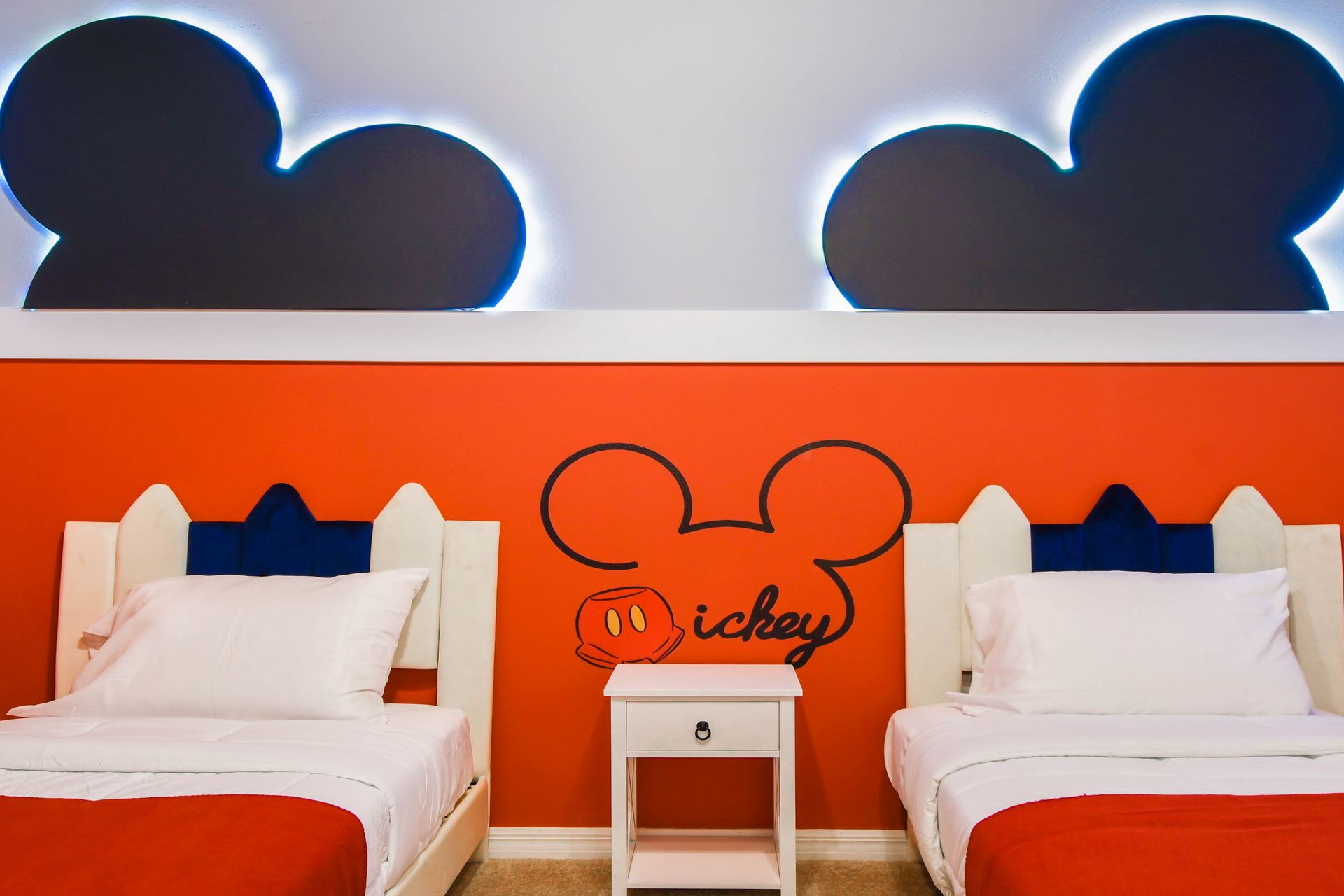 Mickey-themed kids’ room with twin beds, bold colors, and playful wall designs.