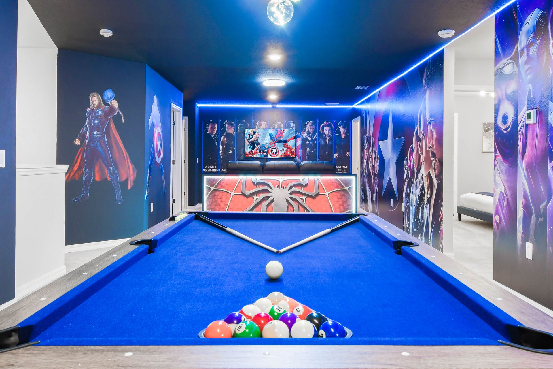 Superhero-themed billiards room with bold wall art, vibrant lighting, and fun vibes.