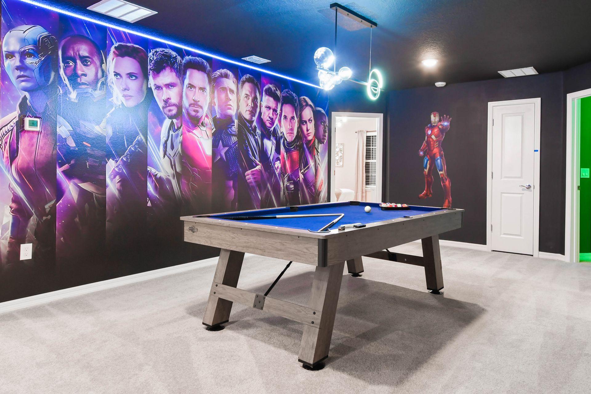 Superhero-themed billiards room with bold wall art, vibrant lighting, and fun vibes.