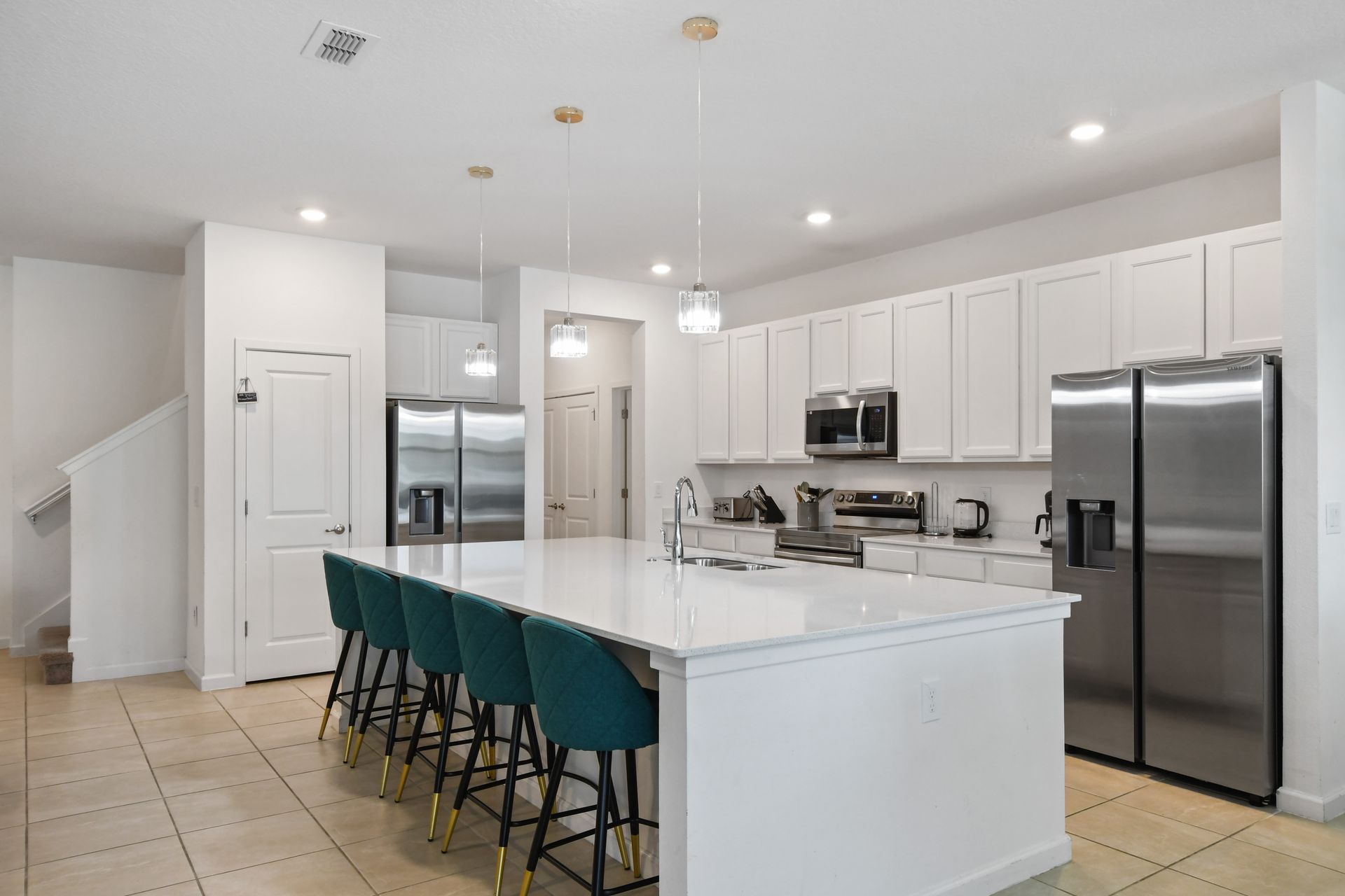 A sleek, modern kitchen with a spacious island, stainless steel appliances, and a breakfast bar with seating for six - perfect for preparing and enjoying family meals.