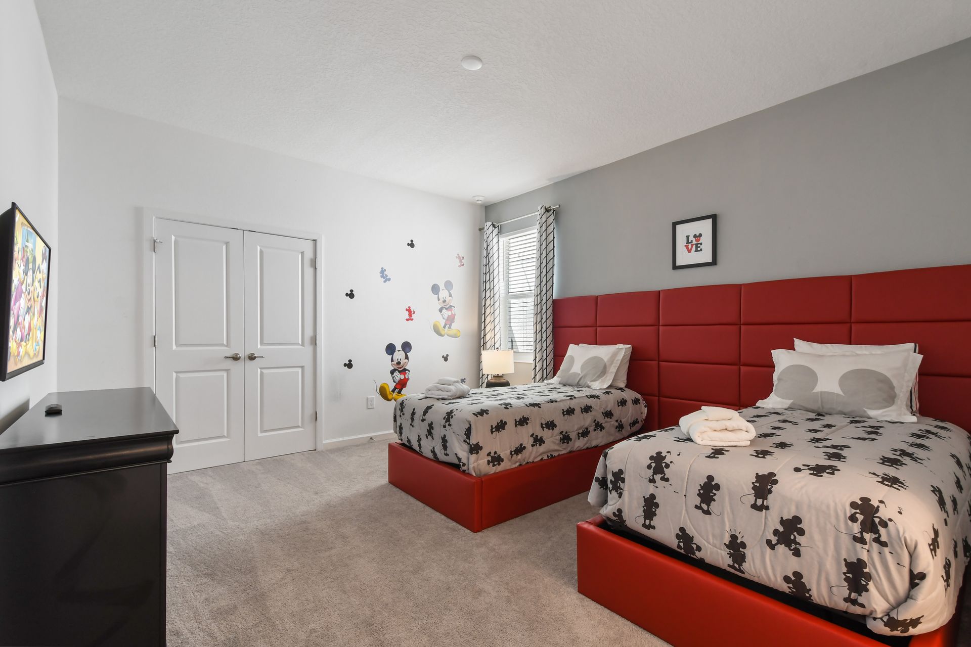 Magical Mickey-themed bedroom with stylish red accents, cozy beds, and playful décor!