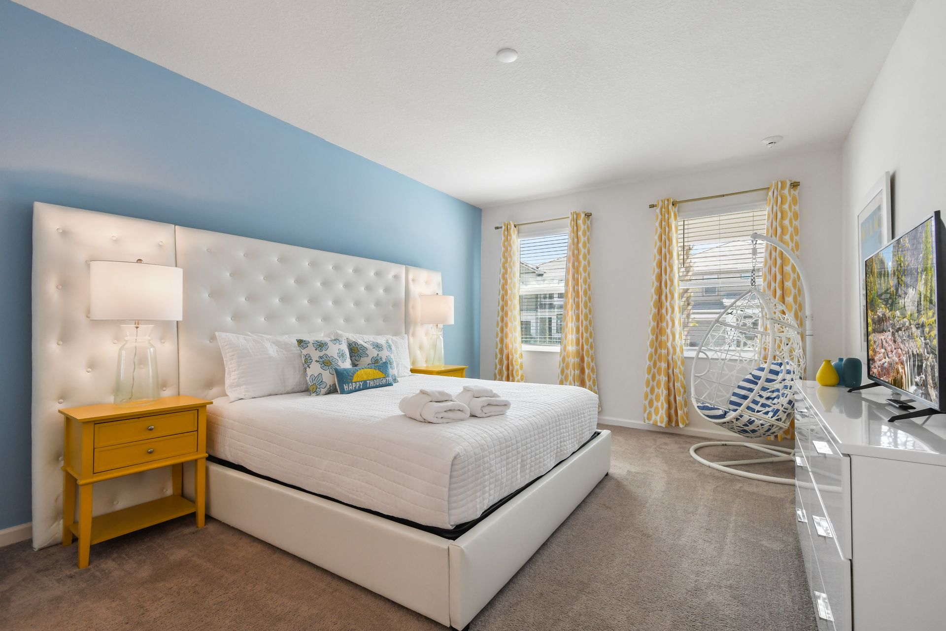 Bright and cheerful bedroom with a plush bed, hanging chair, and sunny décor!