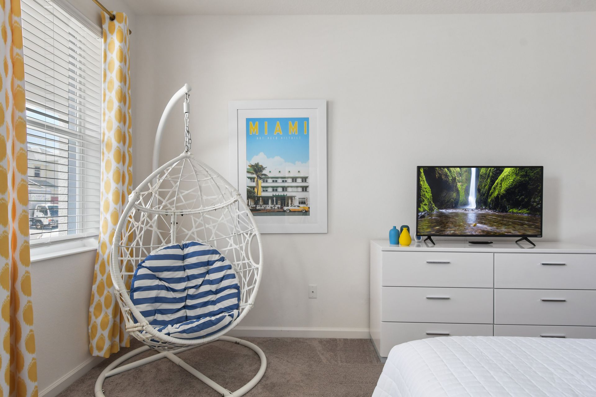 Bright and stylish bedroom with a cozy hanging chair, vibrant décor, and a Miami vibe!
