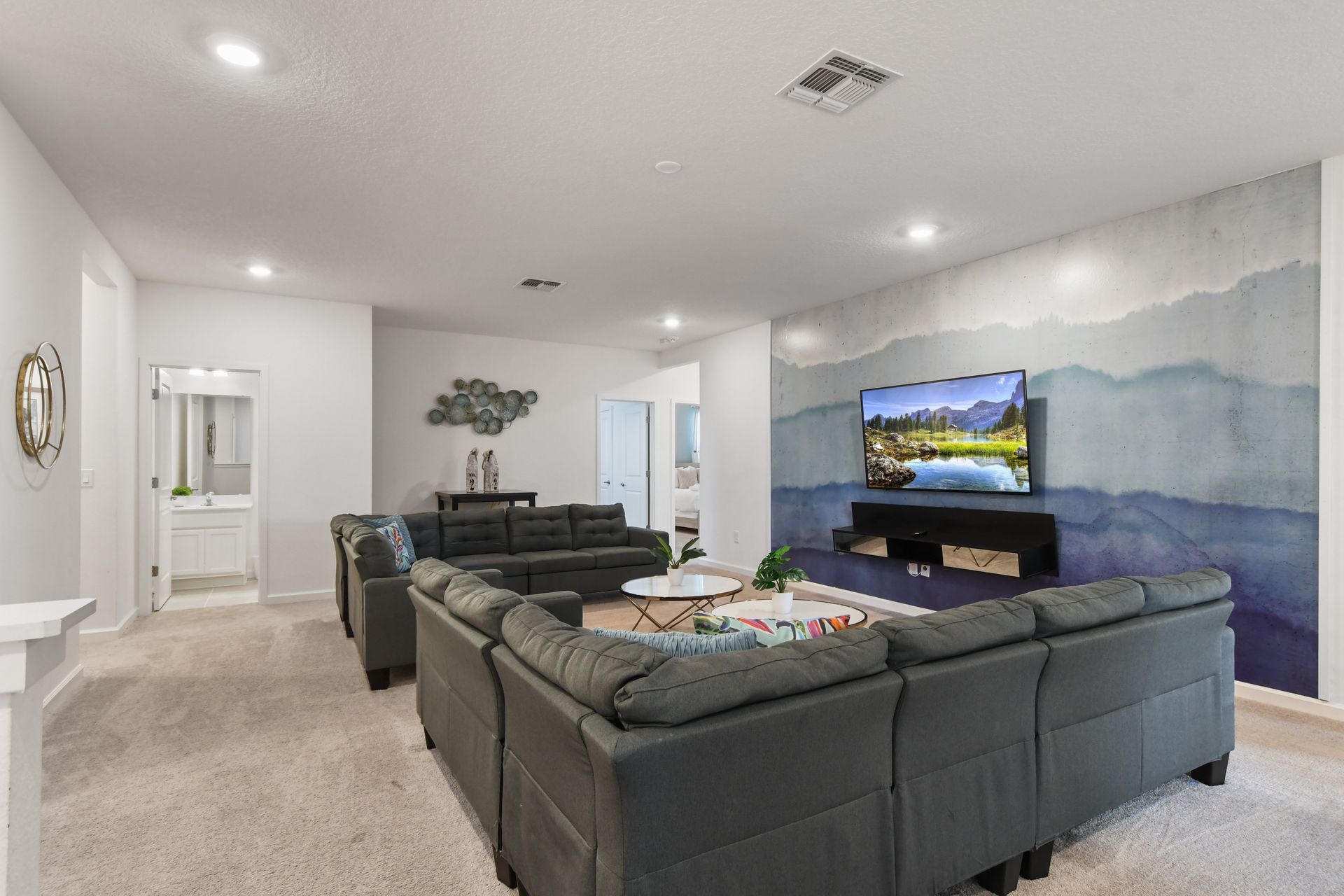 Stylish upstairs lounge with plush seating, a scenic accent wall, and a cozy vibe!