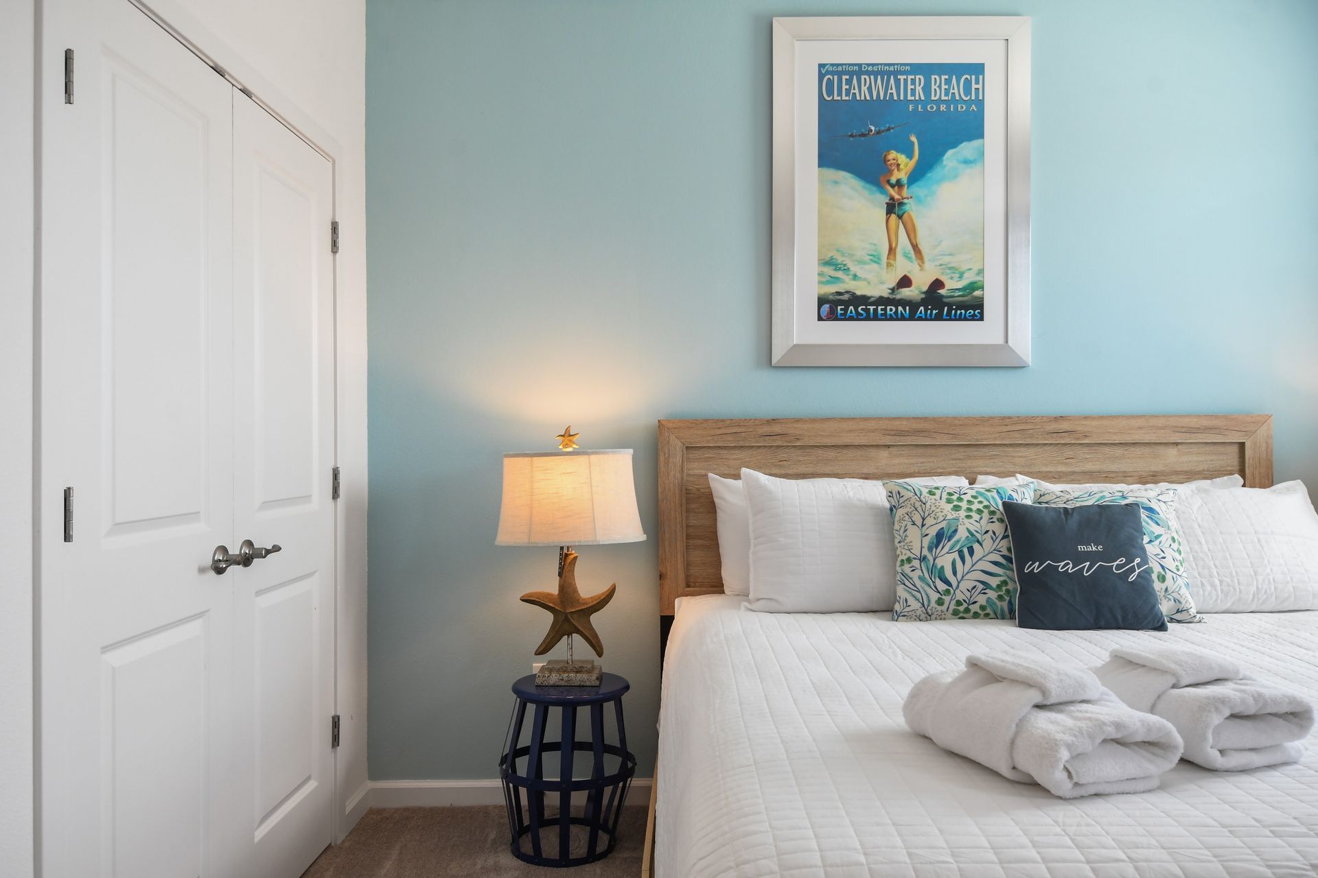 A beautifully decorated coastal-themed bedroom featuring a soft blue accent wall