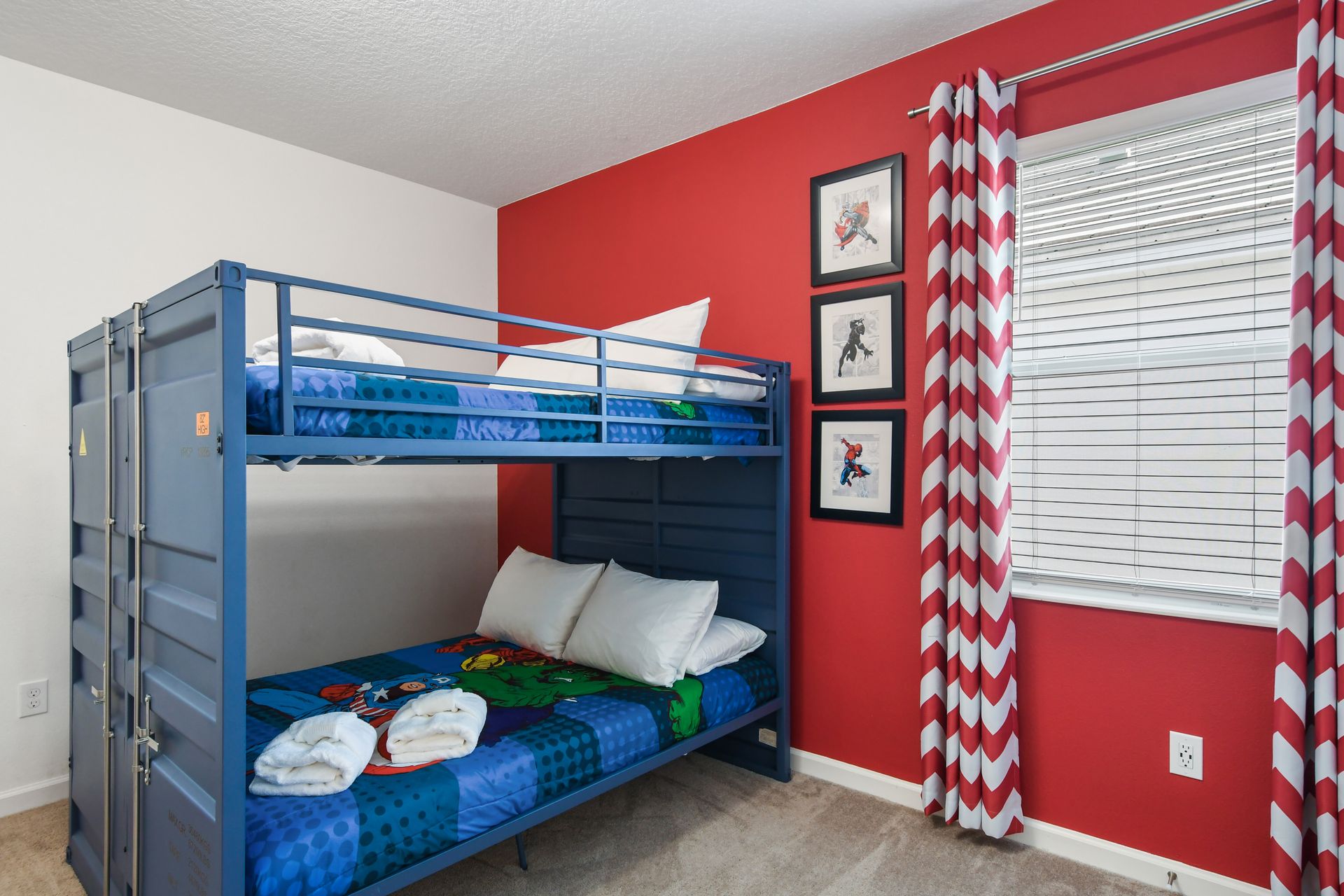 A superhero-themed kids' bedroom featuring a bold red accent wall