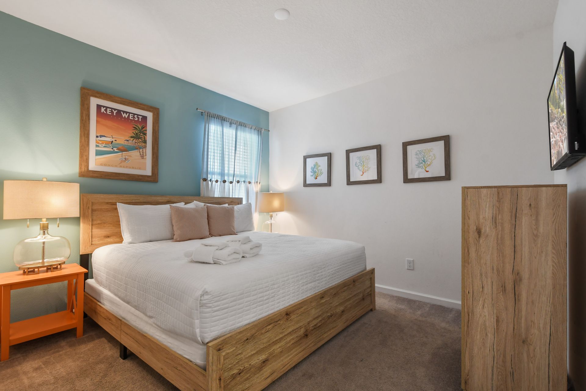 This cozy bedroom embraces a Key West coastal theme, featuring a soft blue-green accent wall
